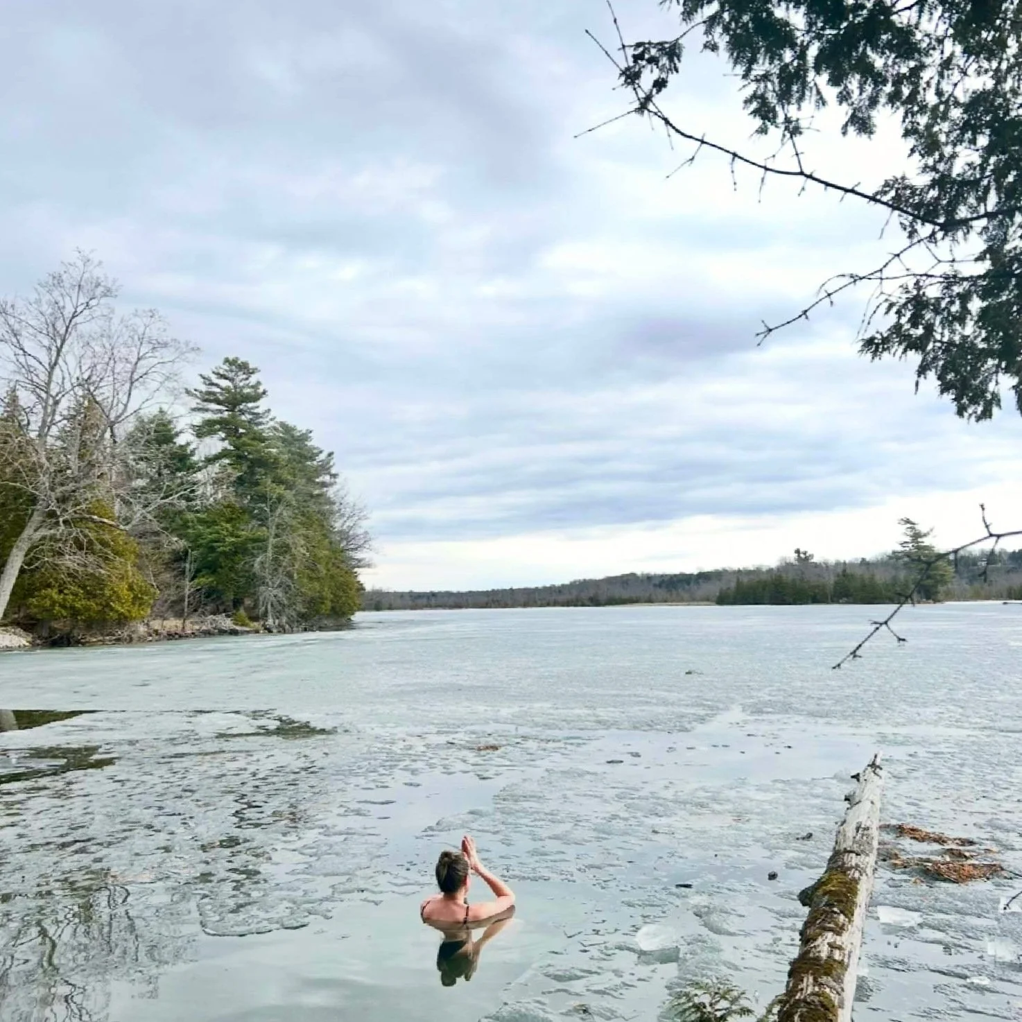 A person sitting quietly in a cold lake surrounded by trees