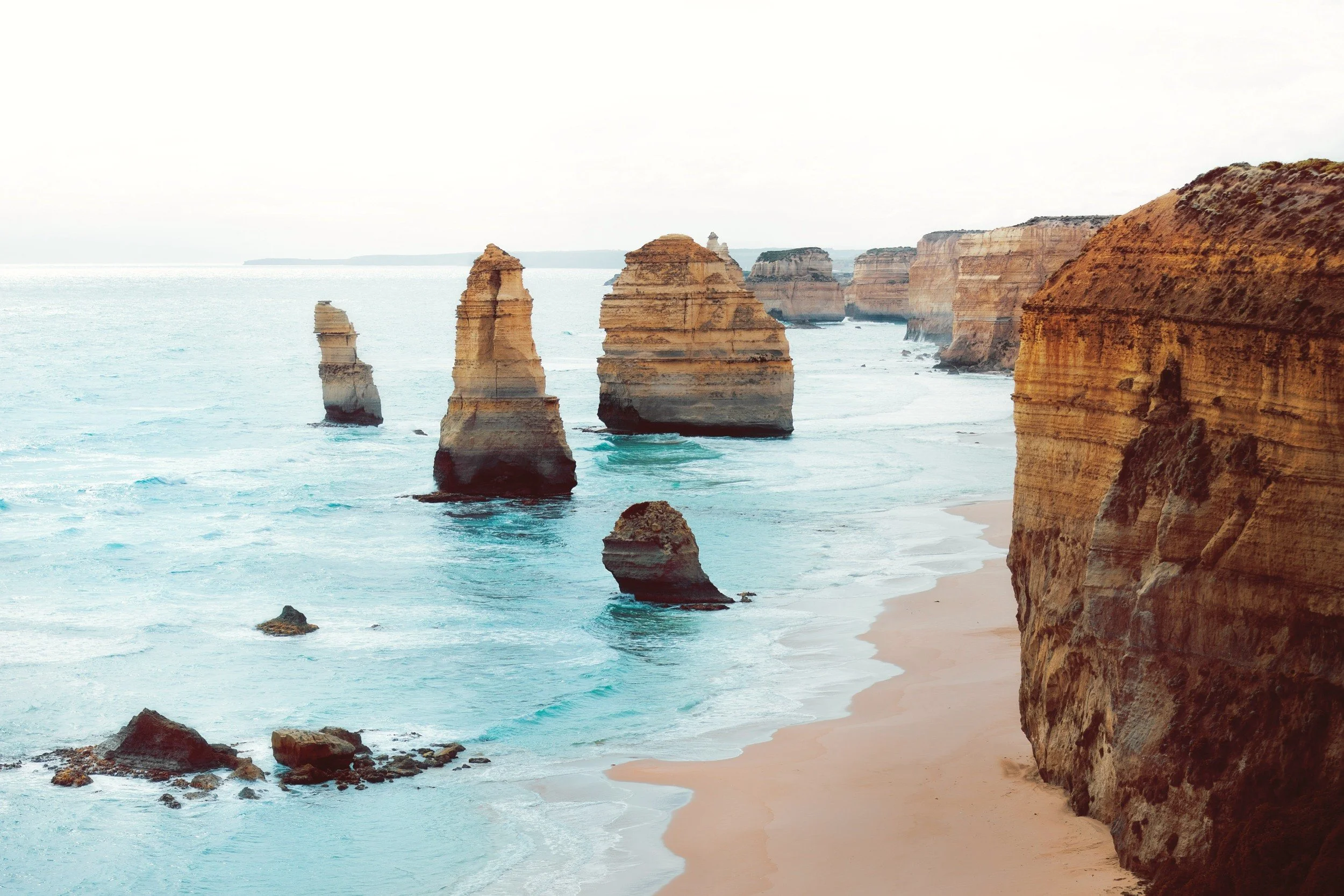 Scenic view of the Twelve Apostles limestone stacks along the Great Ocean Road in Australia, with cliffs and sandy beach.