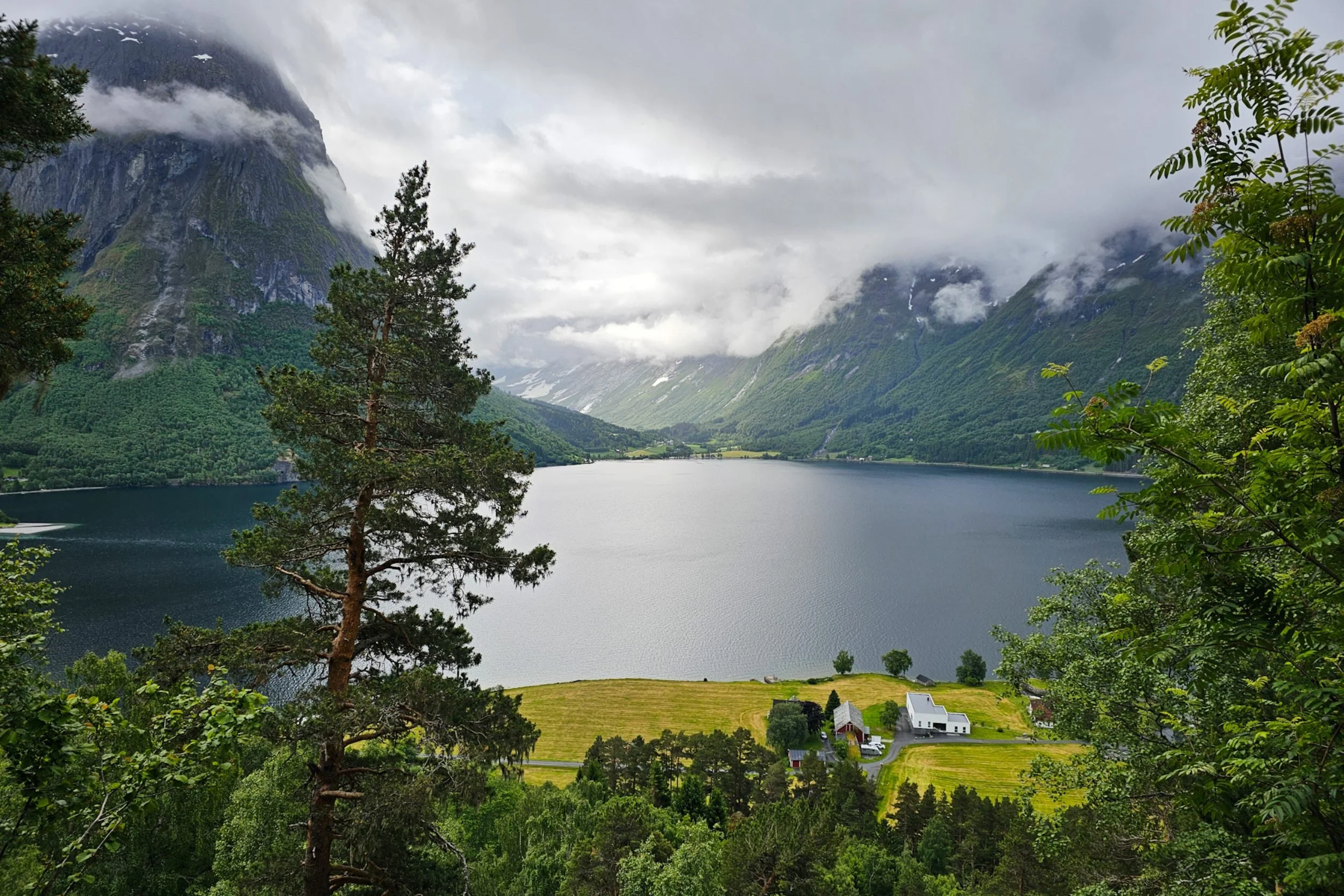 Small lakeside town surrounded by towering hills engulfed with white clouds