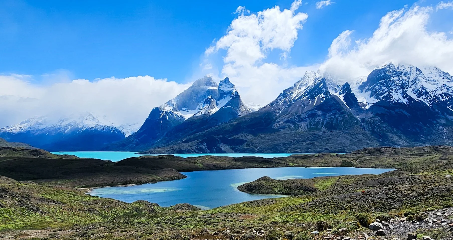 Jagged snow capped mountains with turquoise blue lakes below.
