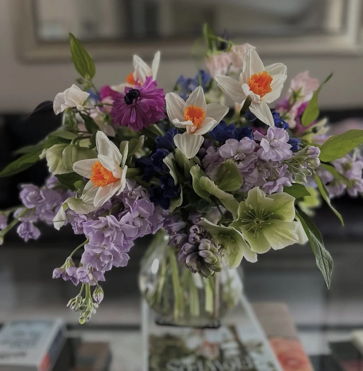 Colorful mixed flower bouquet in a glass vase on a table.
