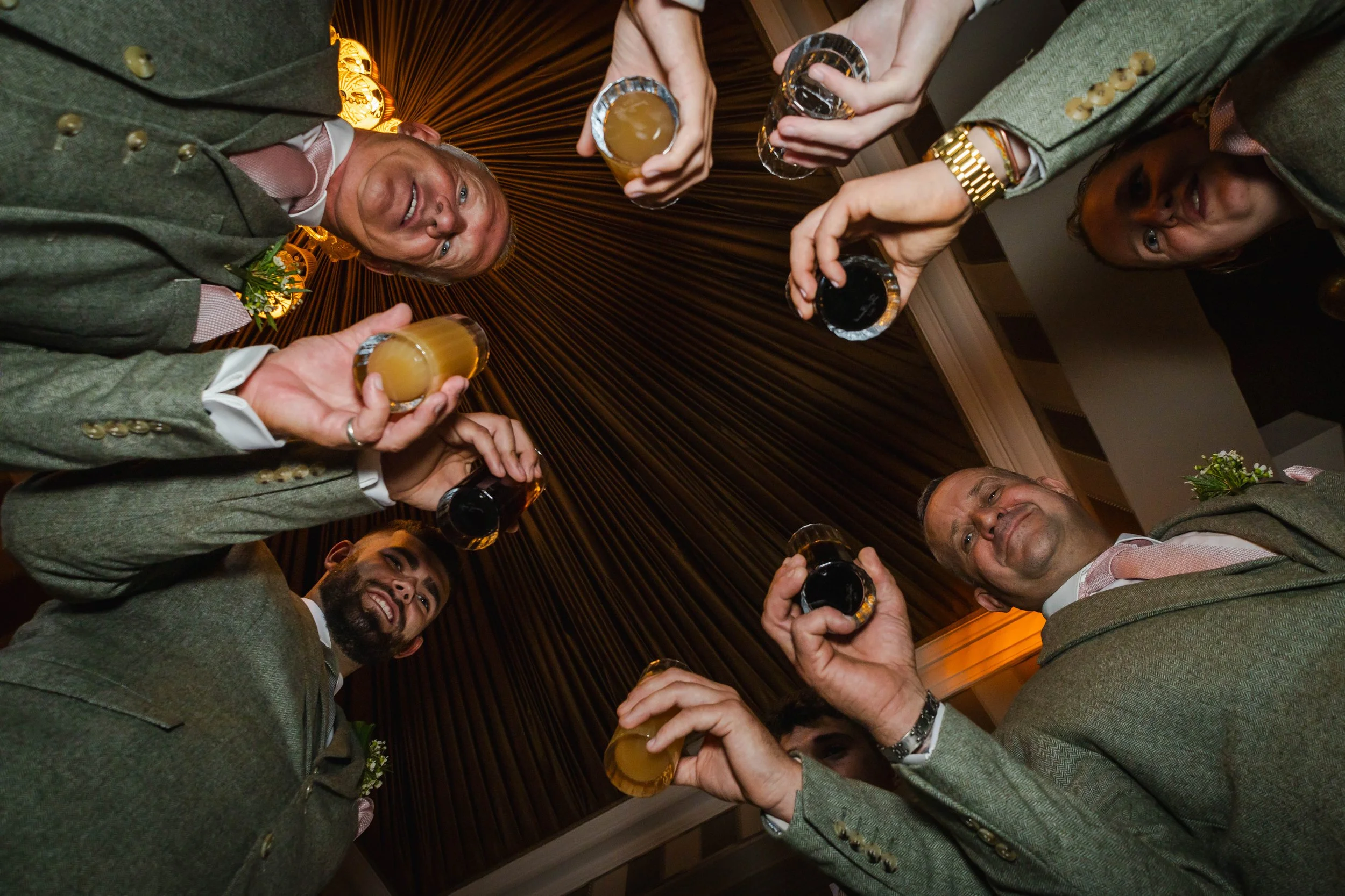 A group of people in formal attire raising glasses for a toast at a celebration or gathering, viewed from below.