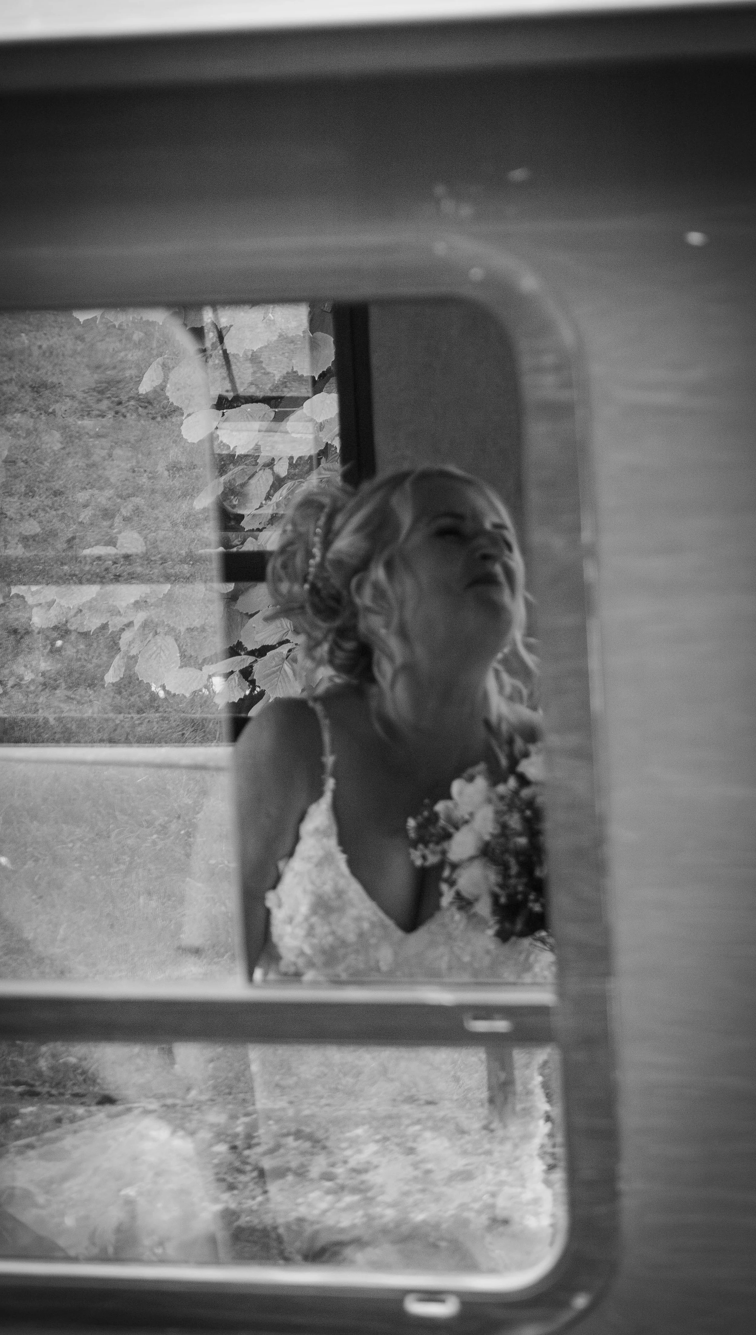 Black and white photo of a woman in a wedding dress looking into a mirror.