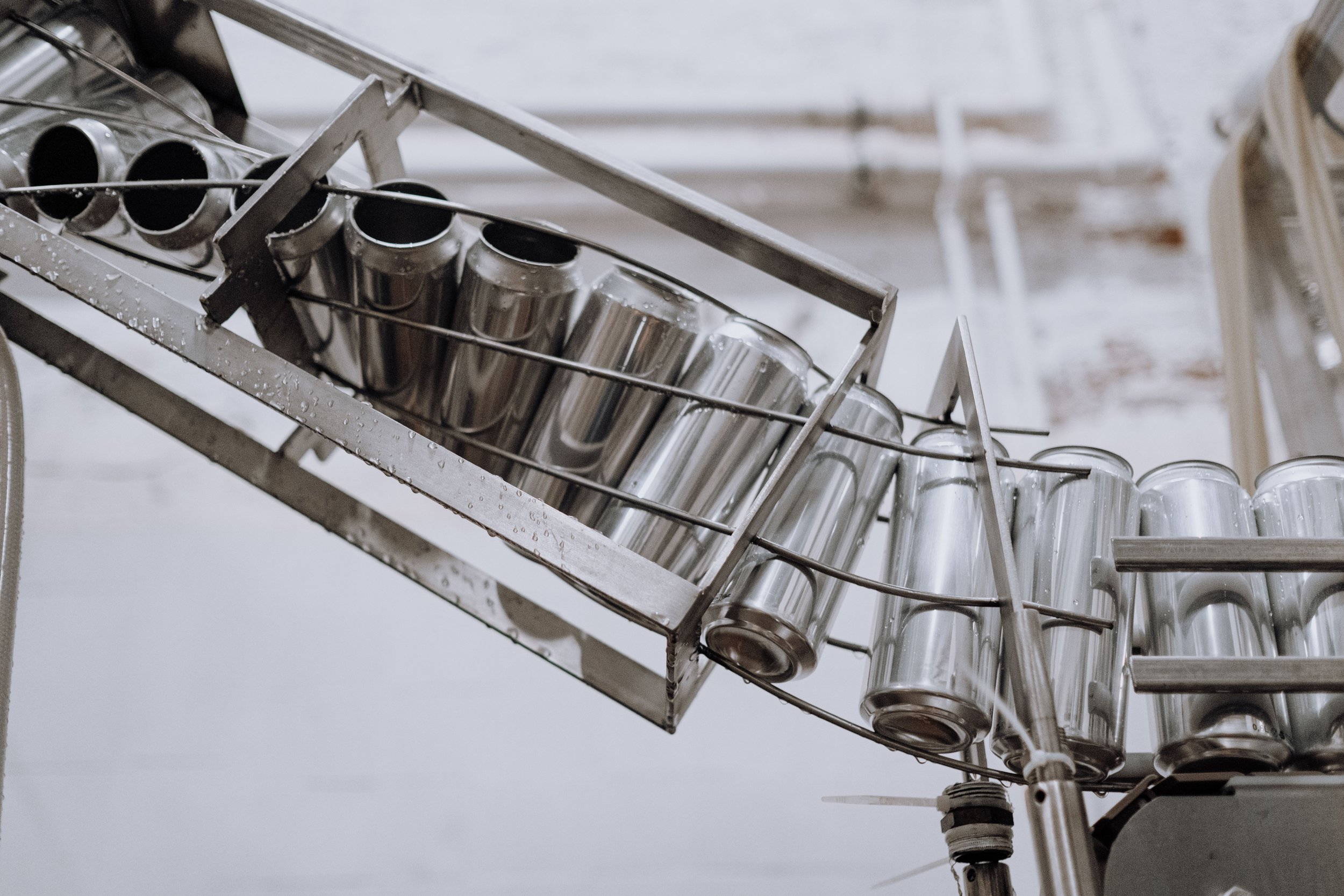 A metal dish rack holding clear glasses, with water droplets on them, mounted on a kitchen wall.