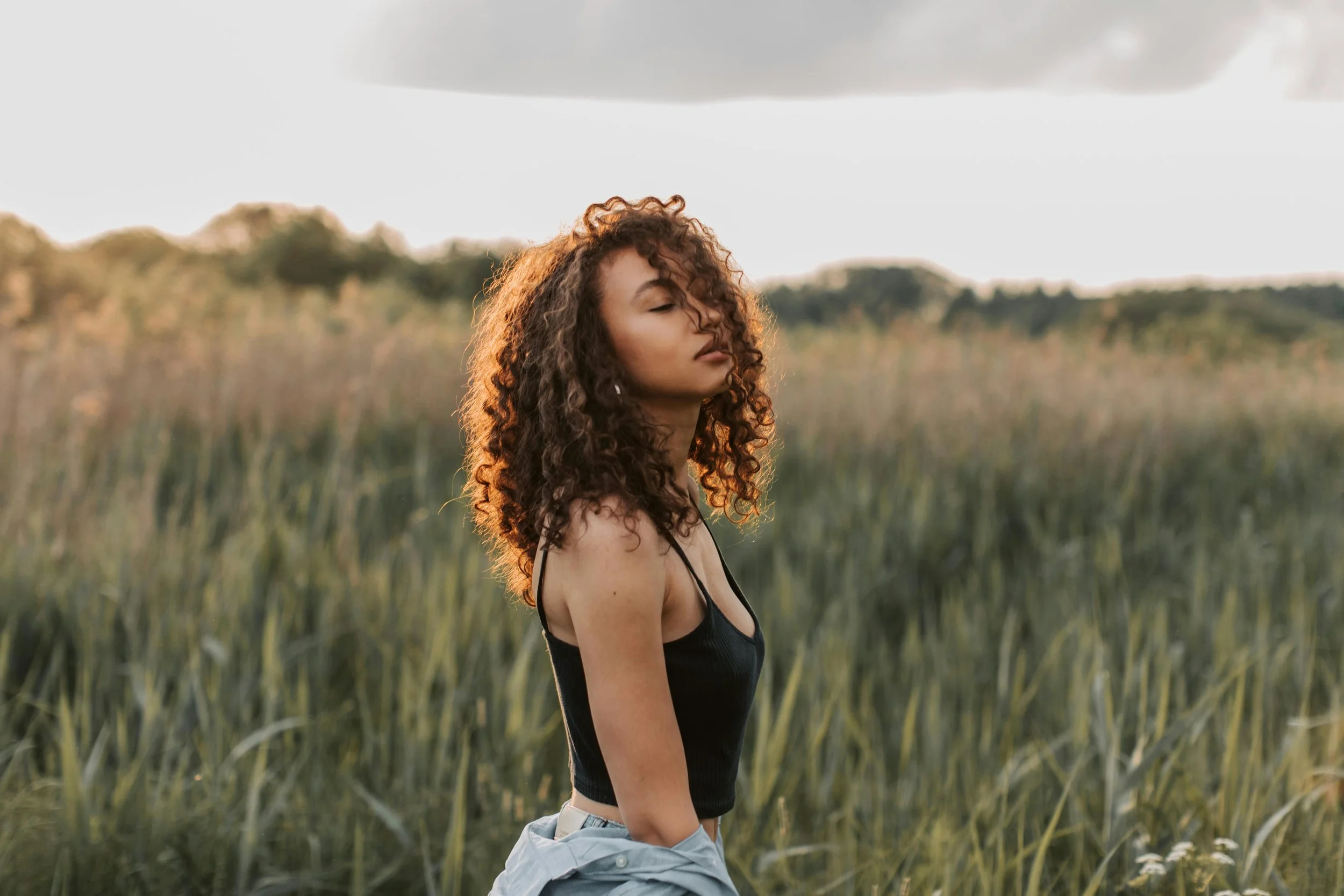 Woman standing in an open field with a calm, relaxed expression, symbolizing peace and emotional well-being in Arizona