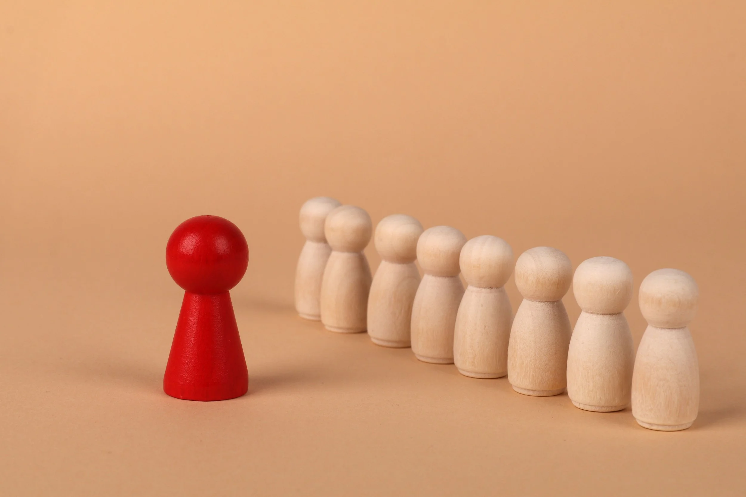 Red chess pawn standing in front of pink pawns, symbolizing anger, emotional intensity, and feeling different from others.