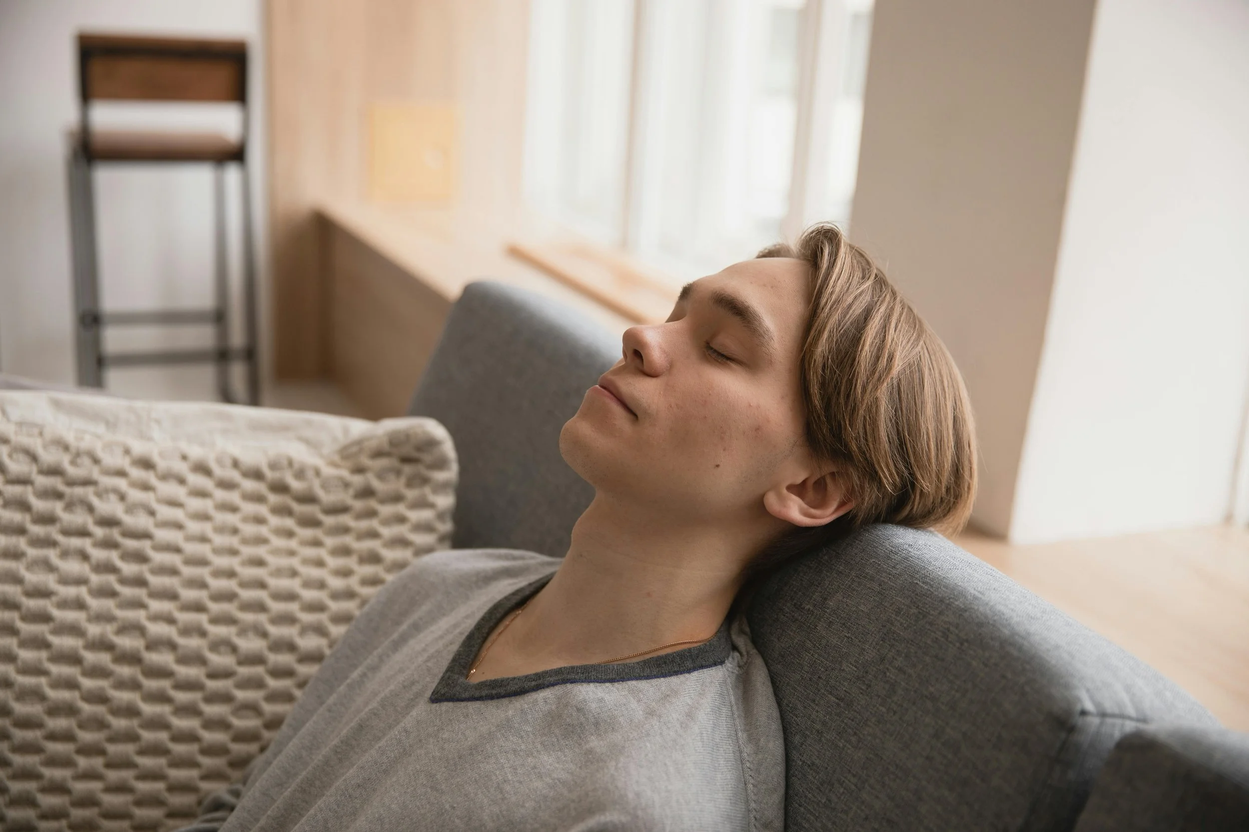 Man relaxing on couch with eyes closed, representing mental health wellness and stress relief in Arizona