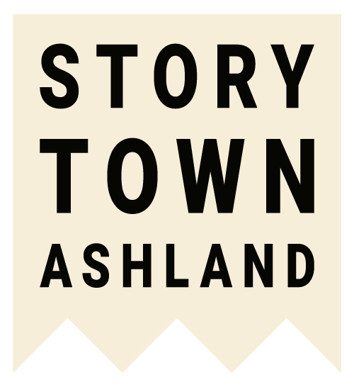 Illustrated sign with the words 'Storytown Ashland' in bold, black capital letters on a cream-colored background with black zigzag edges at the bottom.