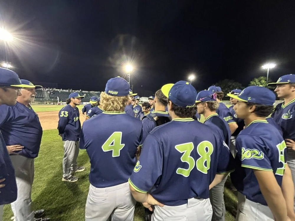 Dr. Skip Flanagan talking with a team huddle on the field at night