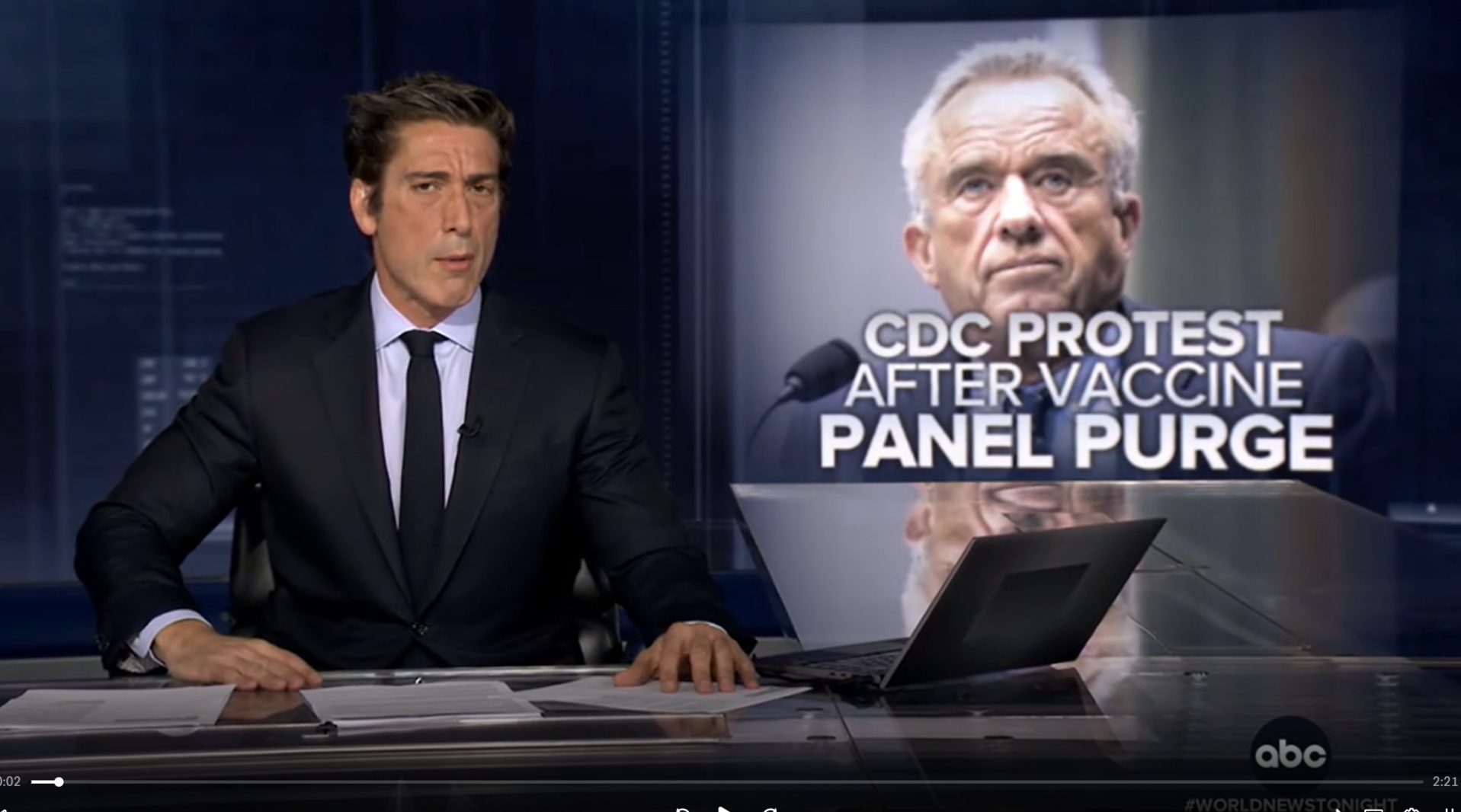 News anchor sitting at a desk during the evening news broadcast, with a large screen behind him displaying a headline about CDC protest after vaccine panel purge.