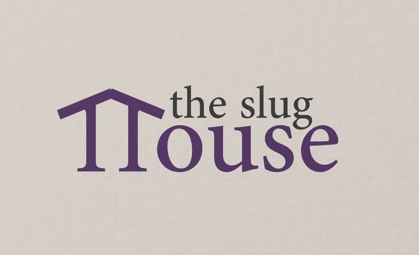 The logo for 'The Slug House' featuring a purple house roof over the word 'house' and the words 'the slug' in black.