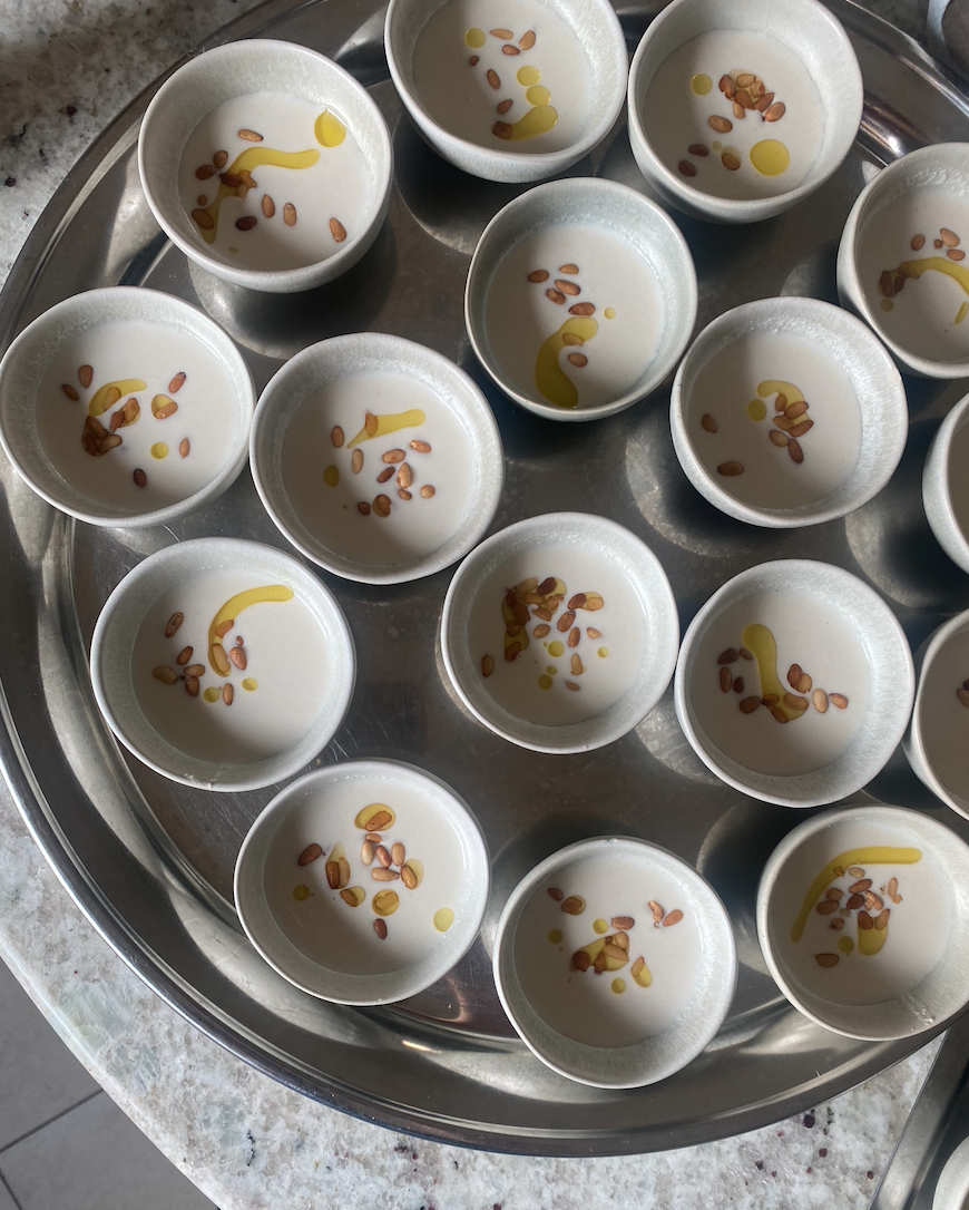 Petits bols de yaourt ou dessert avec des graines et de l'huile d'olive sur une plaque en acier inoxydable.