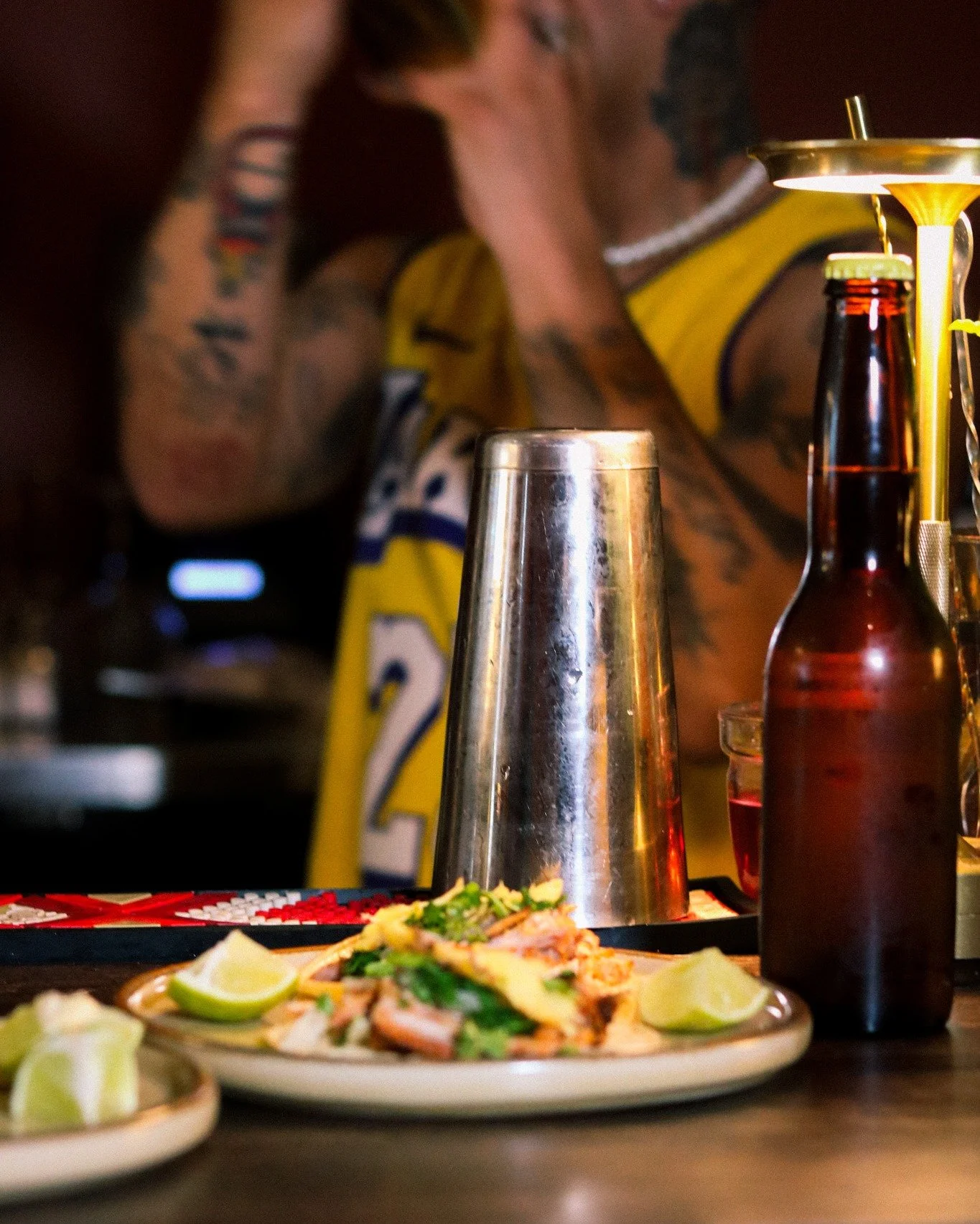 Drink in one hand. Taco on the plate.
Cold beer, shaker mid-pour, lime ready on the side &mdash; this is what a proper night looks like.
In Mexico, you don't pick between eating and drinking. They happen at the same table, with the same people, at th