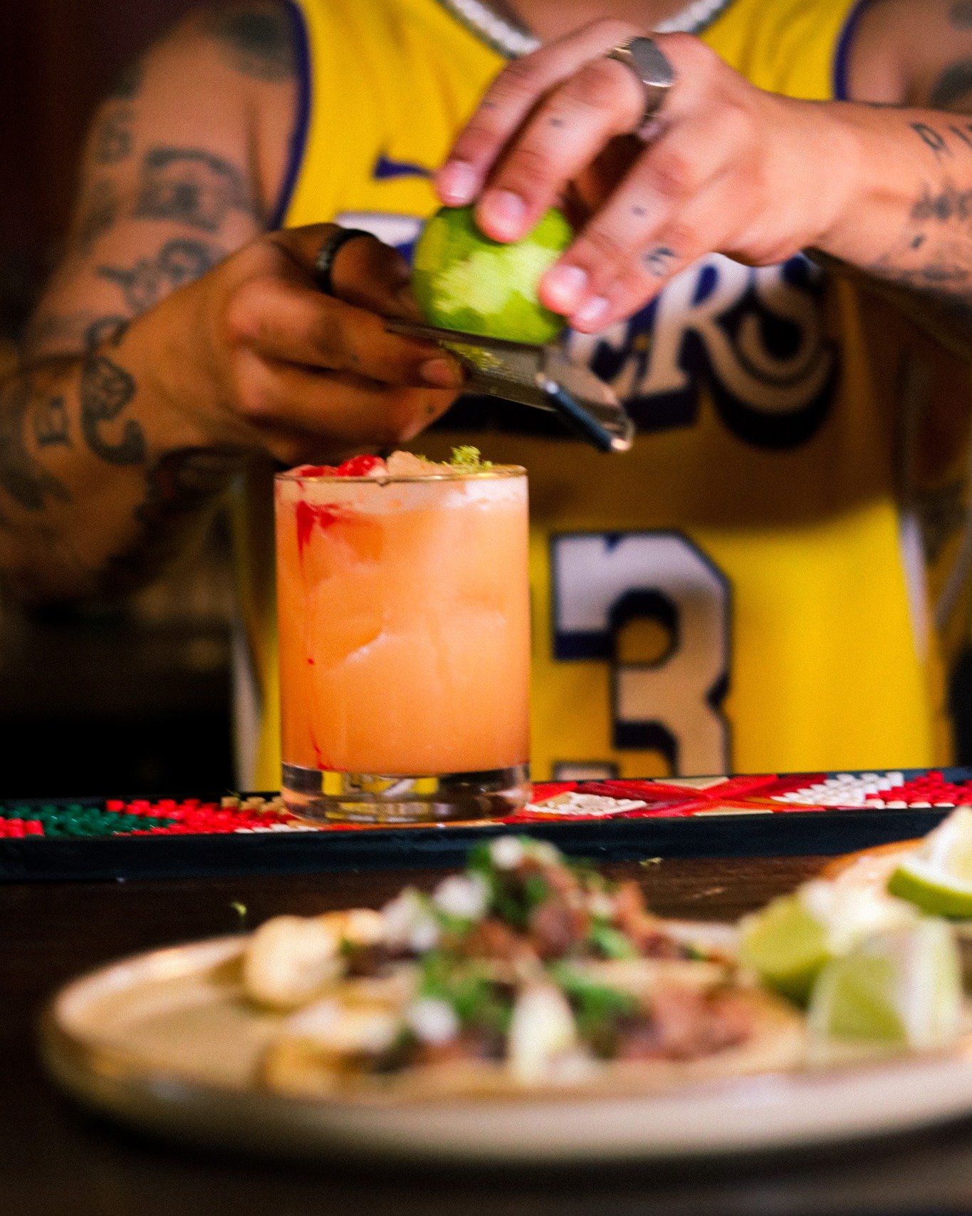 In Between Flags &mdash; the cocktail named for the meaning of Pantitl&aacute;n itself.
Tequila meets maple whiskey. Lime meets ginger. Mexico meets the place that's now home.
Two worlds in one glass, finished with a fresh lime zest under low light.
