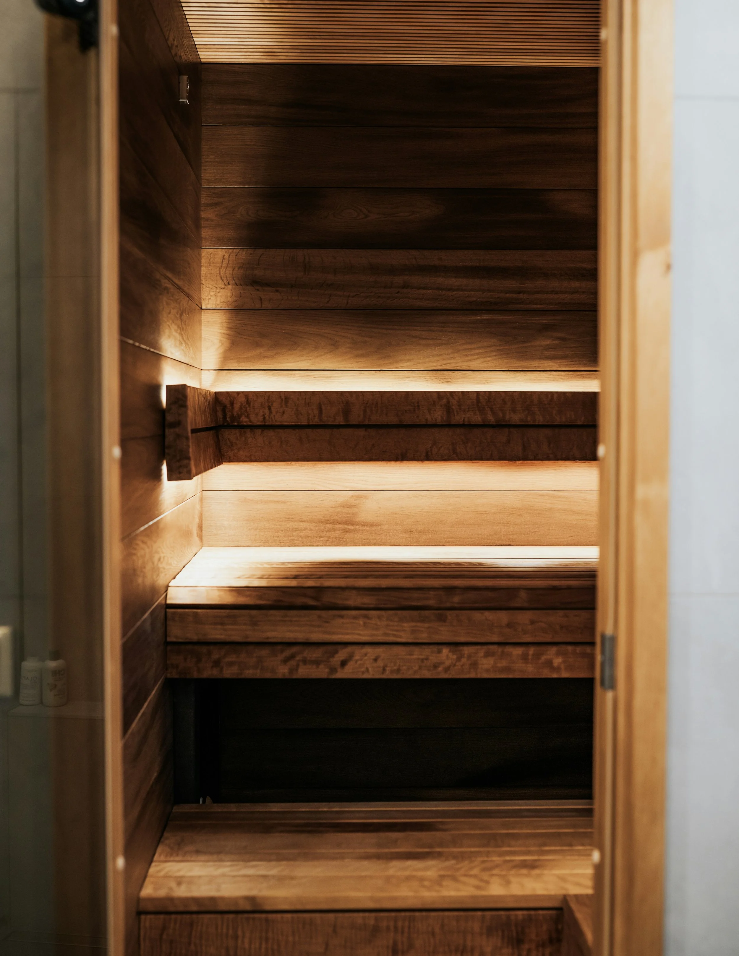 Intérieur d'une armoire en bois sombre avec étagères en bois clair, éclairée par une lumière douce.