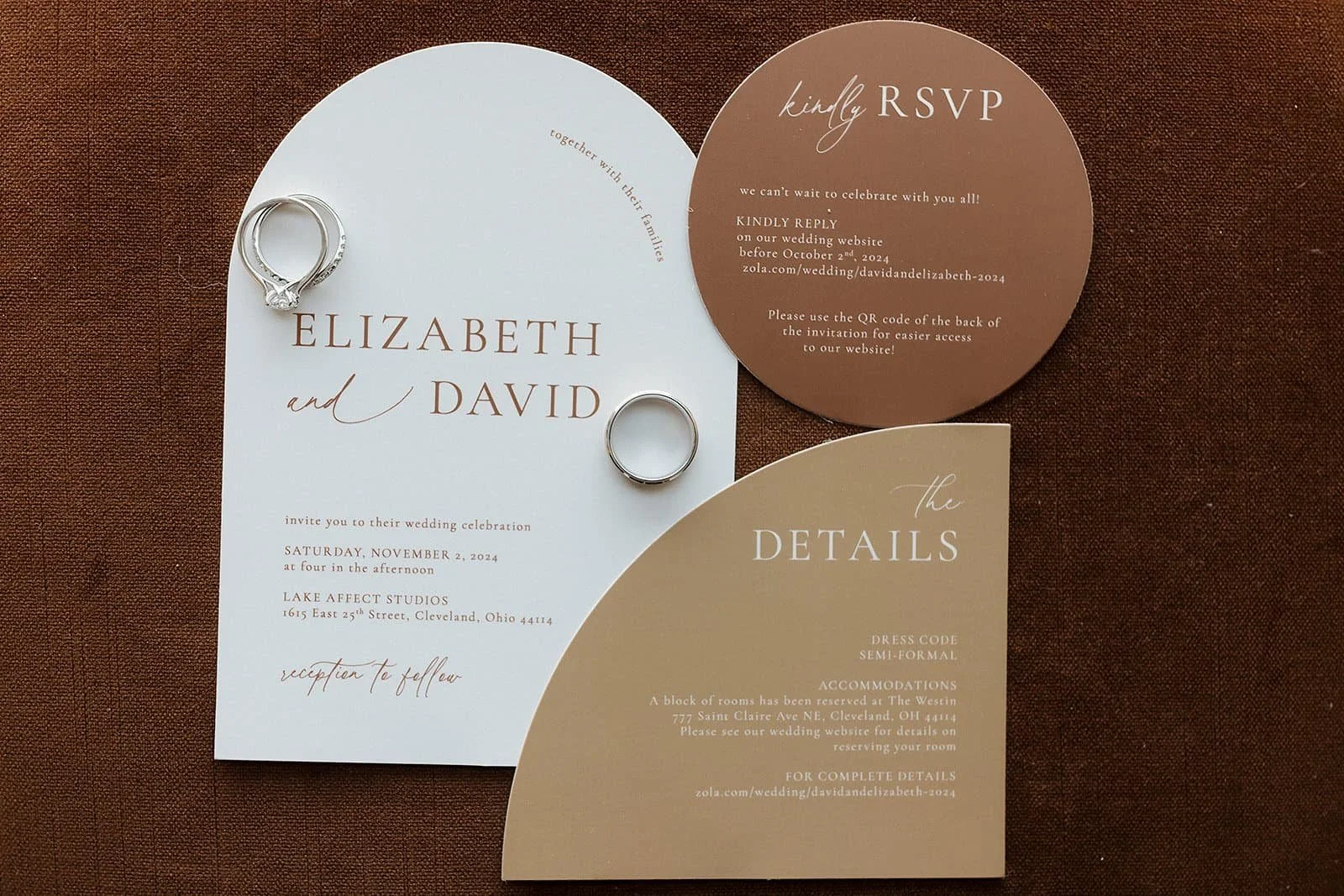 Wedding invitation suite with rings placed on top. The suite includes an invitation card, RSVP card, and details card in neutral tones.