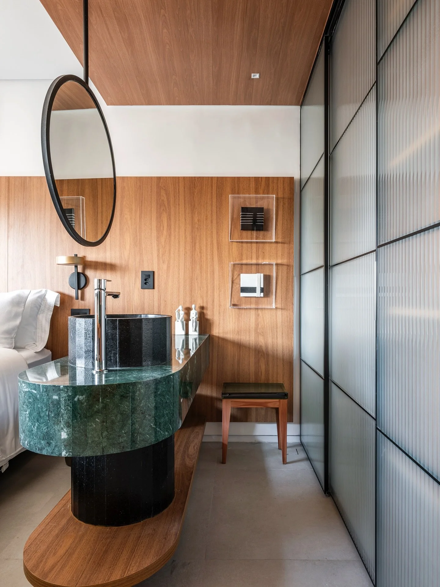 Madeira e m&aacute;rmore &mdash; dois materiais naturais e atemporais &mdash; s&atilde;o os protagonistas deste ambiente.
⠀
A porta de vidro canelado conecta o banheiro ao dormit&oacute;rio, permitindo que a luz circule e os espa&ccedil;os se integre