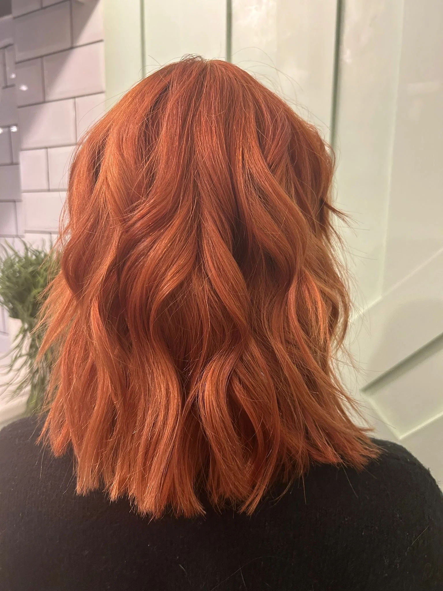Red wavy shoulder-length hair seen from the back.