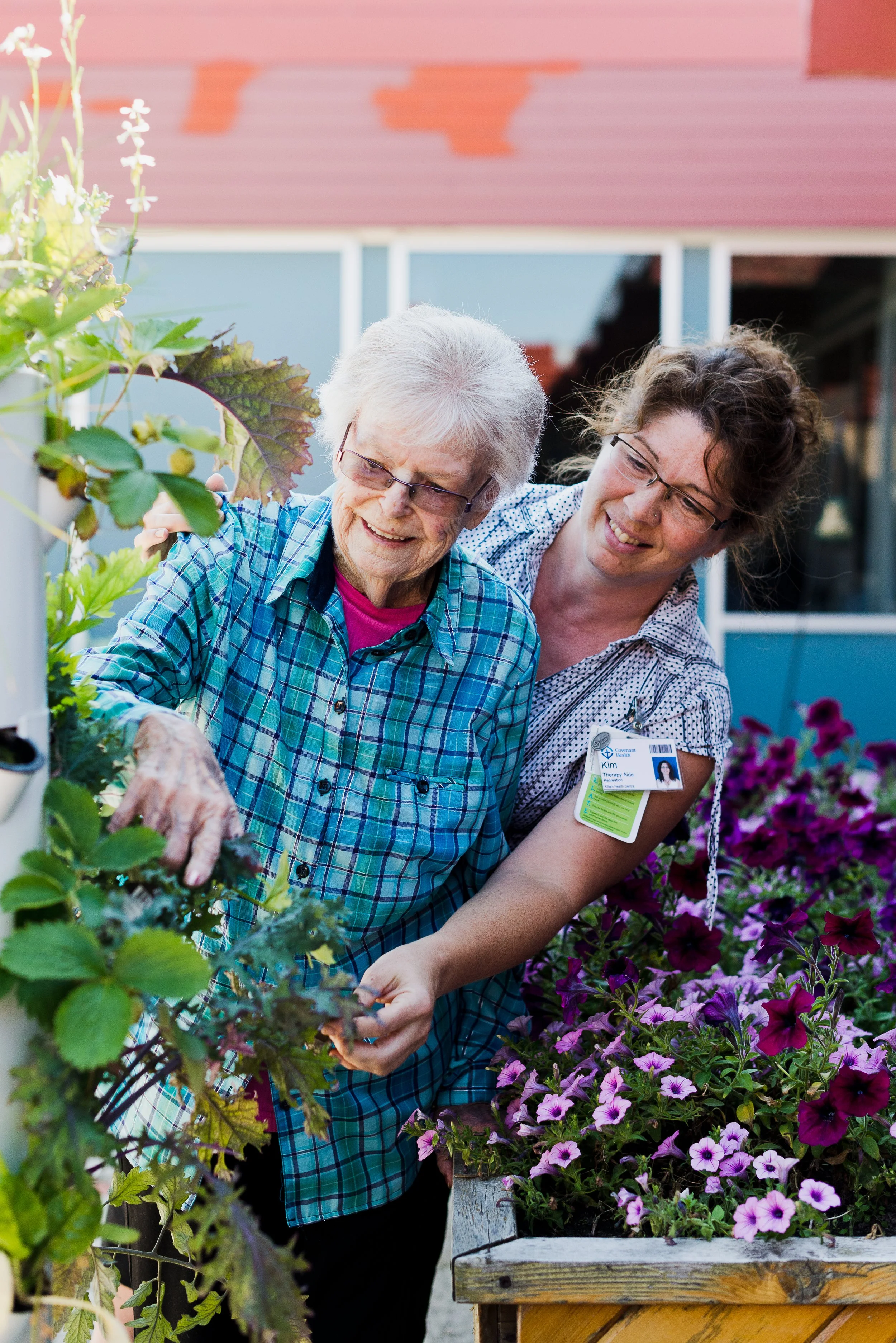 Covenant Health Staff and a senior looking at plants in the garden.