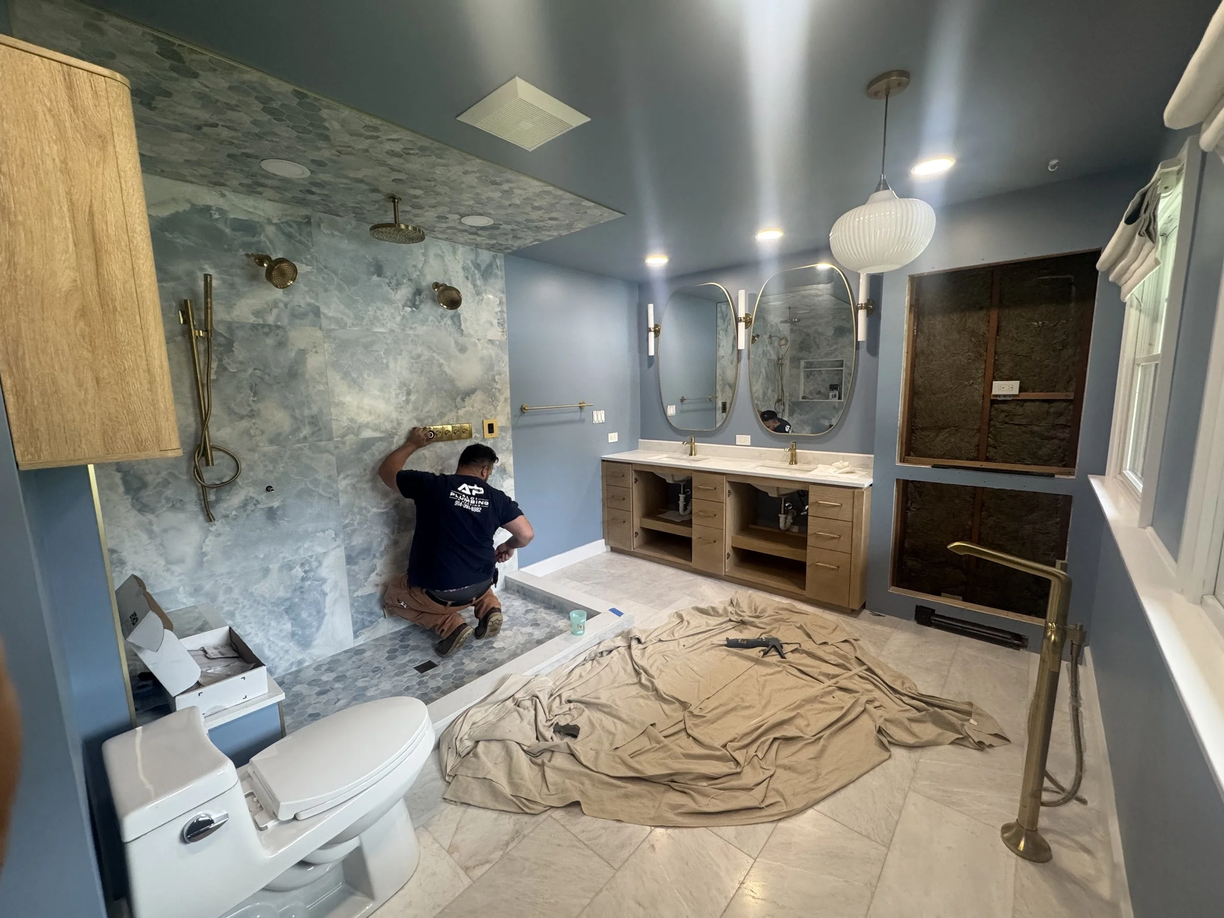 Plumber completing bathroom plumbing during a residential renovation