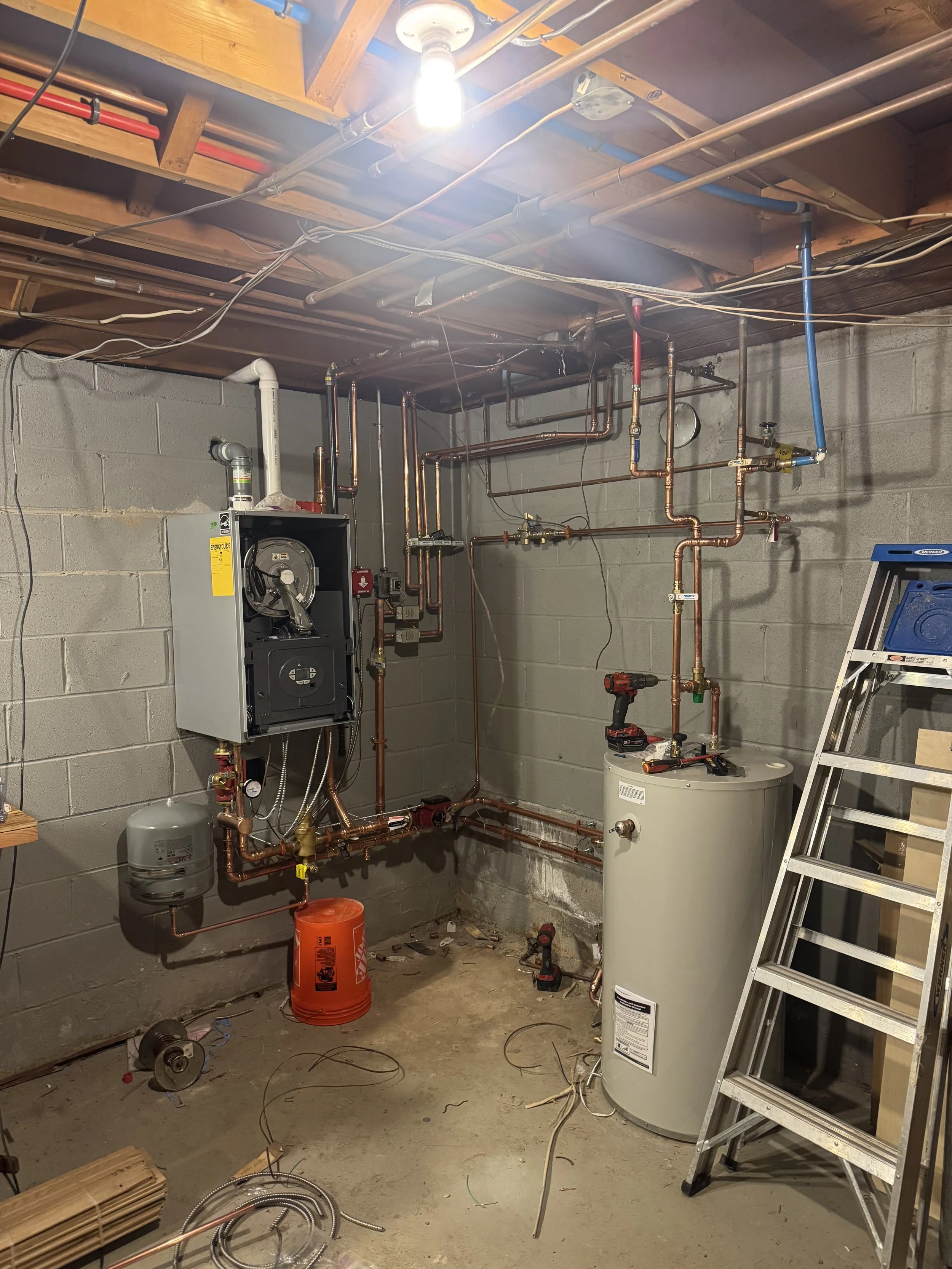 Boiler and water heater installation with copper piping in a basement mechanical room