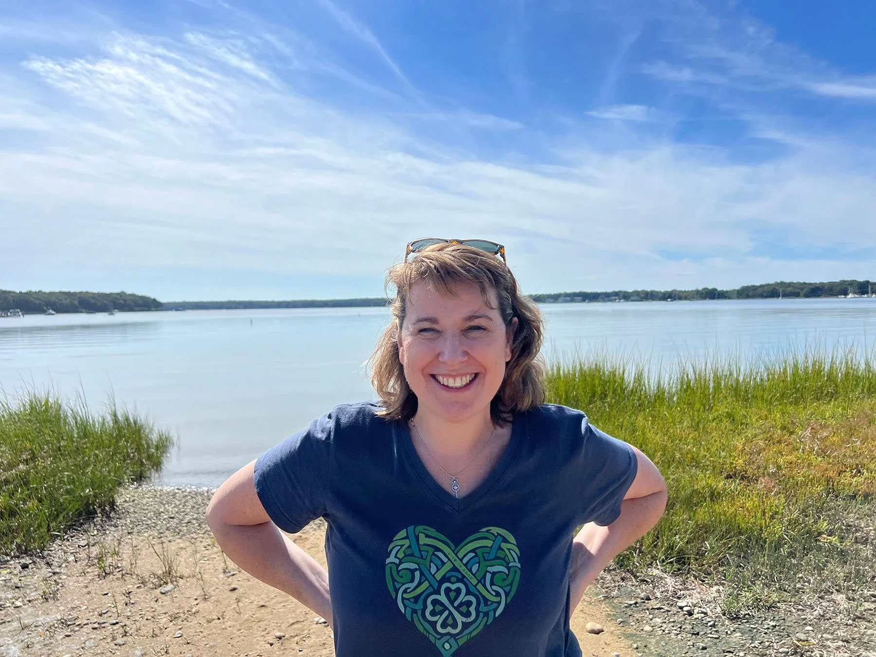 The owner of Mandeville Mental Health Counseling -- Julie -- smiles in a blue shirt as she stands in front of the ocean.