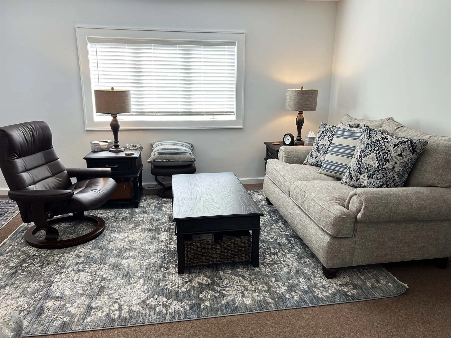 The Mandeville Mental Health Counseling grief counseling office, a bright and spacious room with a cozy tan couch and patterned pillows.