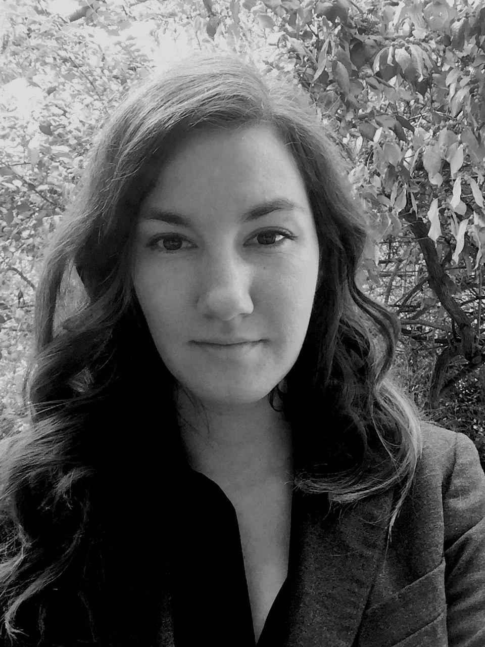 Rebecca Wright with wavy hair, wearing a blazer, standing outdoors in front of trees as Joel Sartore Photography liaison officer to the Photo Ark Foundation