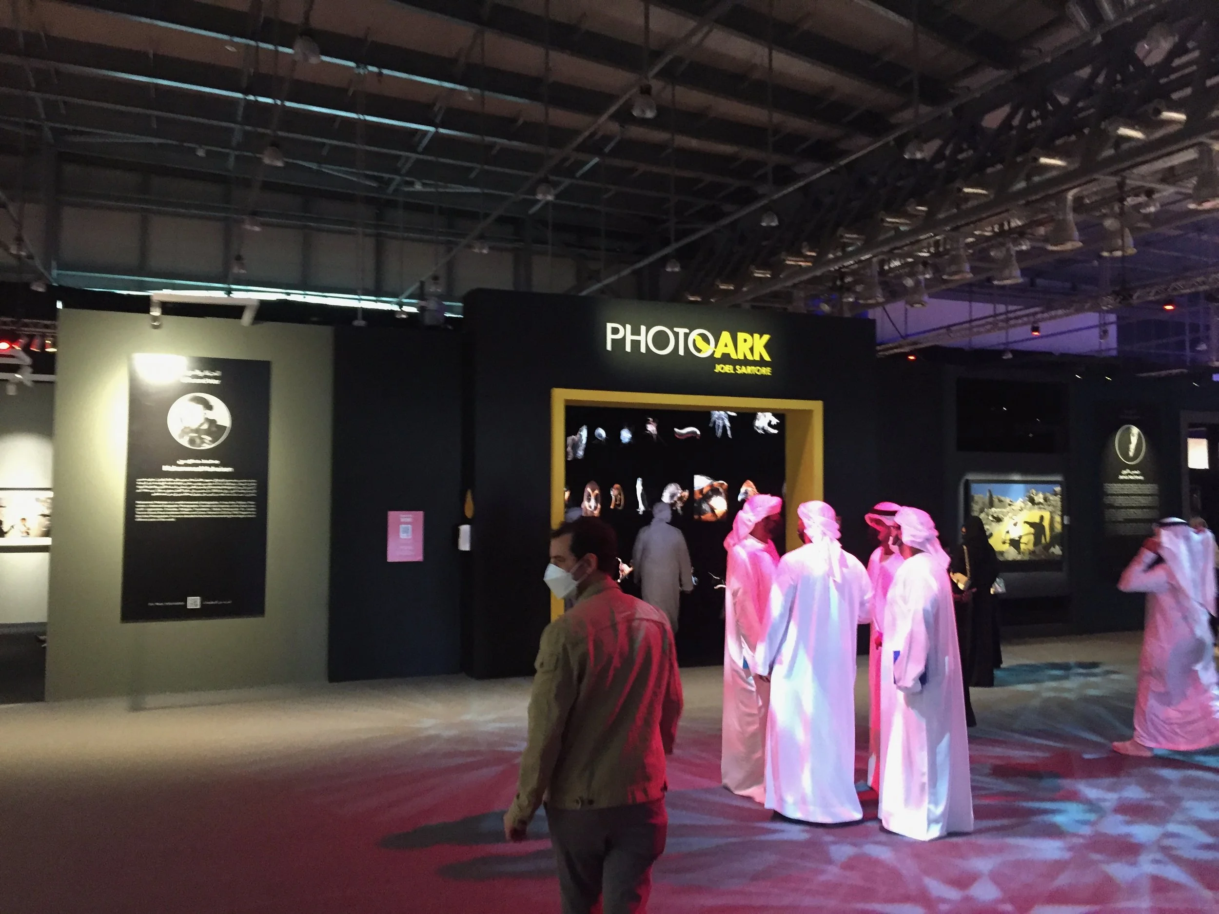 People dressed in traditional Middle Eastern white robes and head coverings visiting a photography exhibit of the Photo Ark in Sharjah, United Arab Emirates.