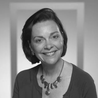 Maura Mulvihill smiling with short dark hair wearing a necklace and a dark top as board chair of the Photo Ark Foundation.