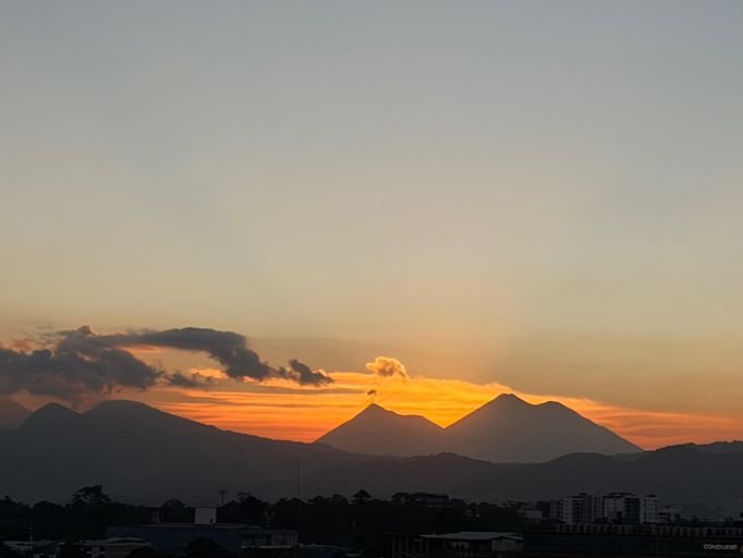 Sunset over a volcanic mountain range in a coffee-growing region.