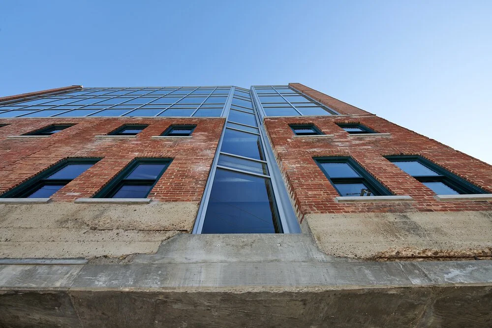 A low-angle view of a modern building with brick and glass exterior against a clear blue sky.