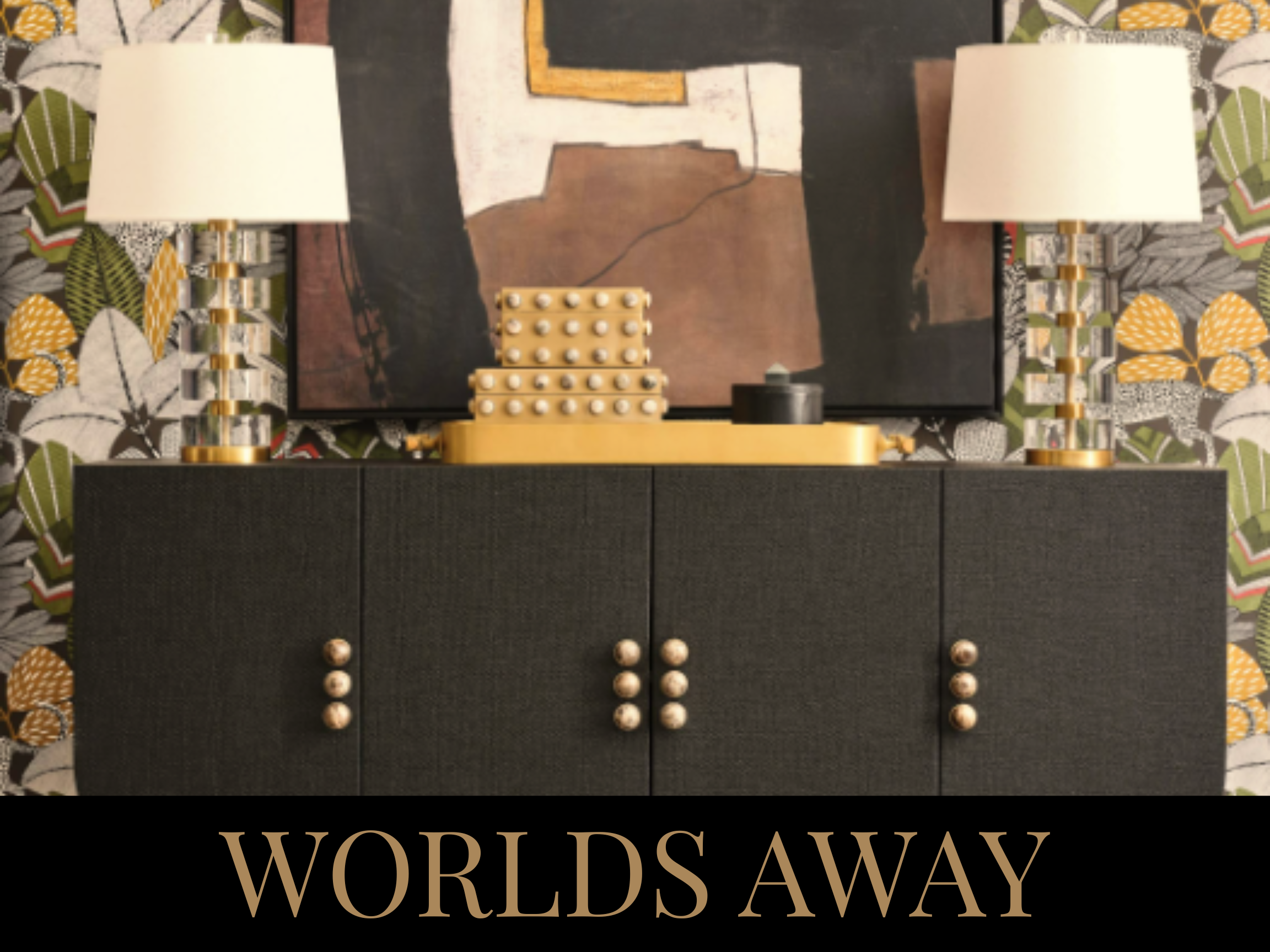 A black sideboard with gold and pearl accents, decorated with two table lamps, an abstract painting, and a decorative box, with floral wallpaper in the background and text "WORLDS AWAY" at the bottom.