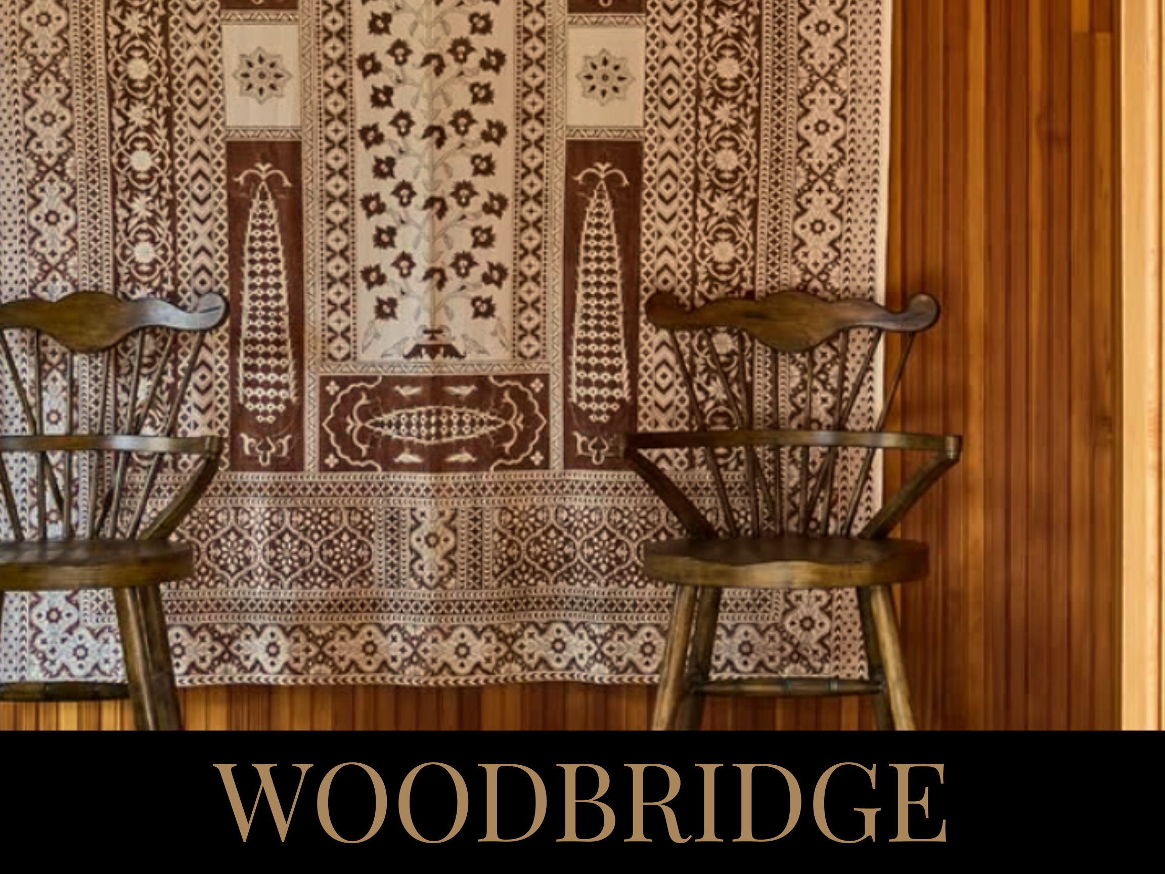 Two wooden chairs in front of a patterned rug with floral and geometric designs, and the word 'WOODBRIDGE' written at the bottom.