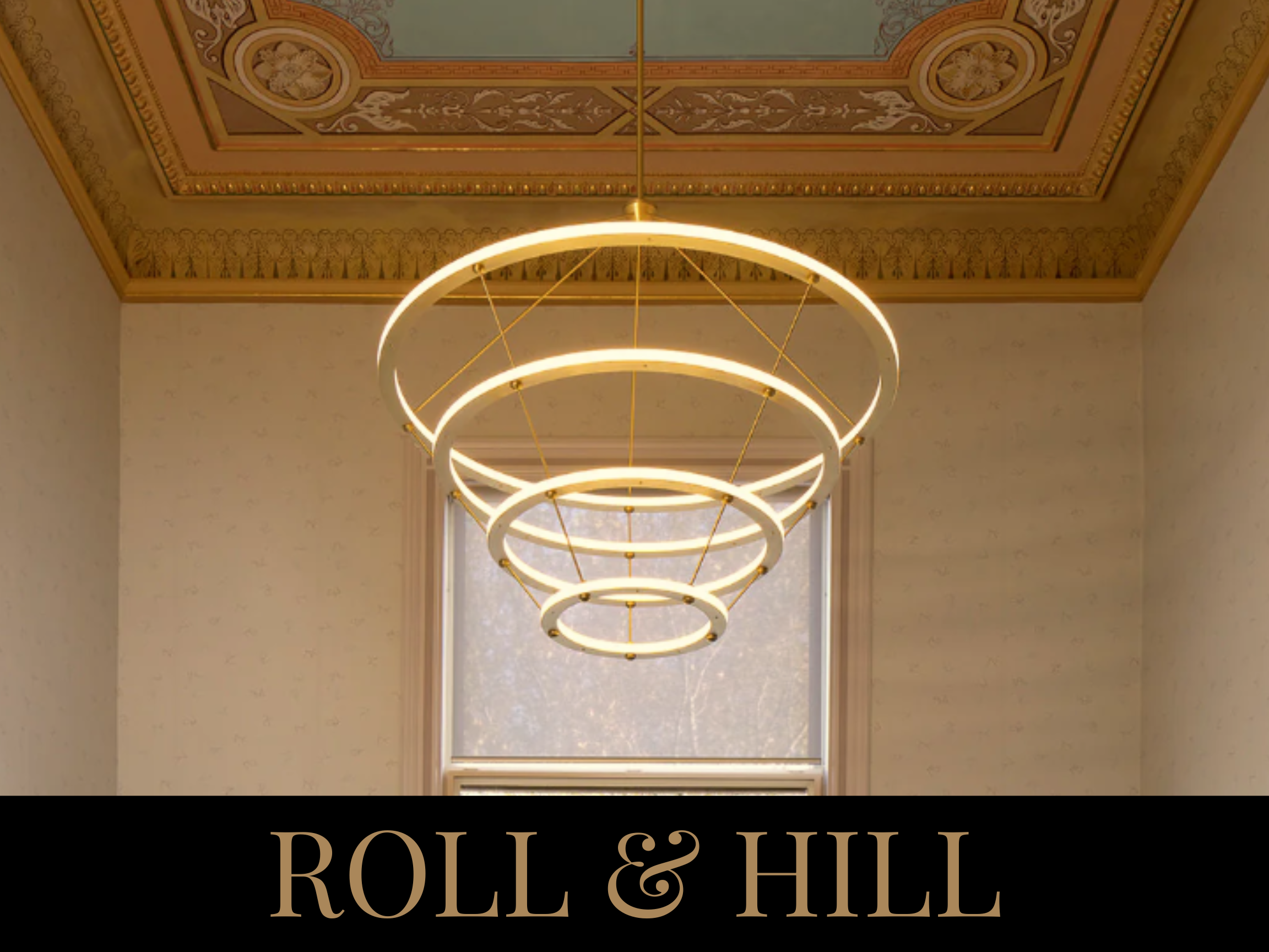 An elegant modern chandelier hanging from a decorated ceiling in a room with a window.