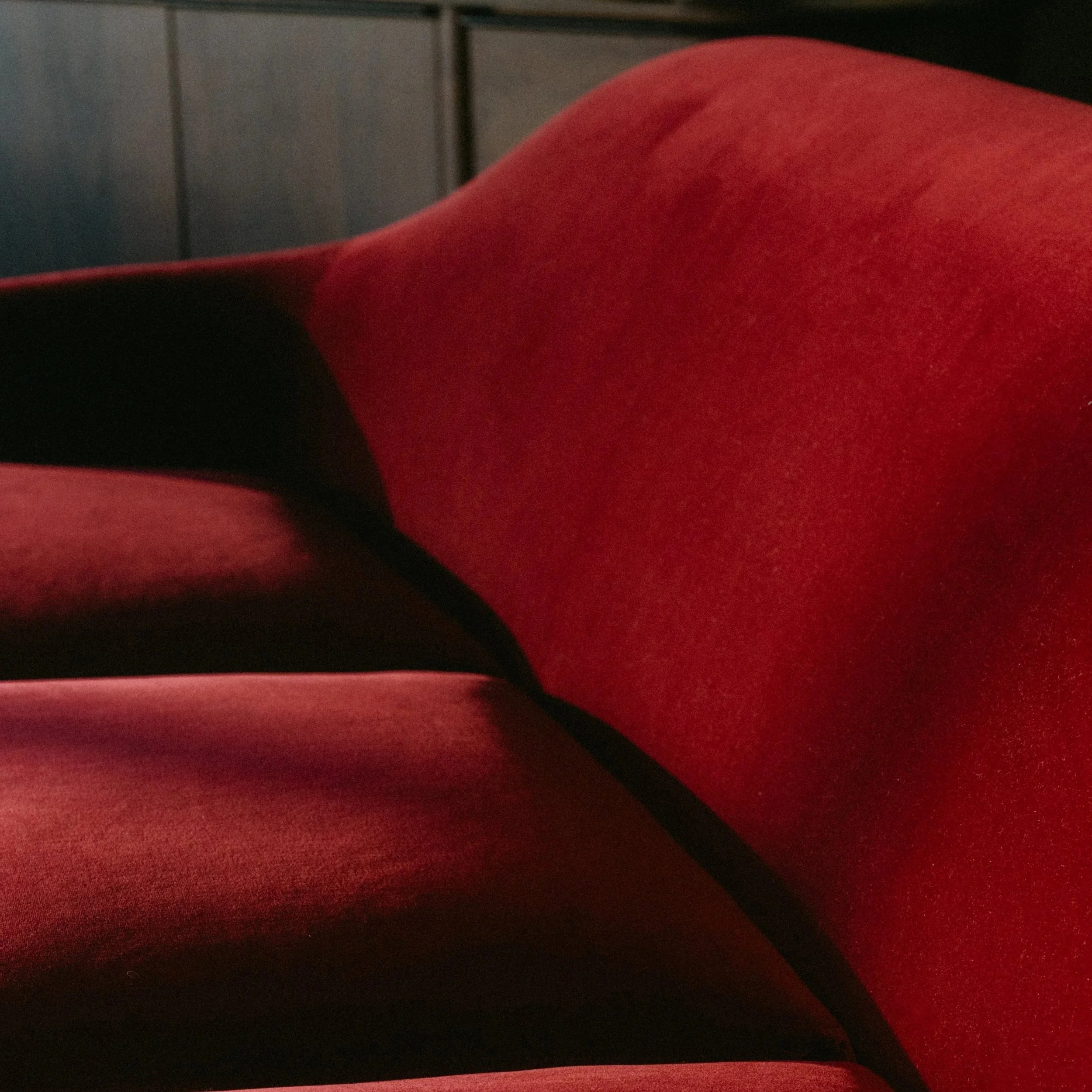 Close-up image of a red velvet upholstered chair with black accents.