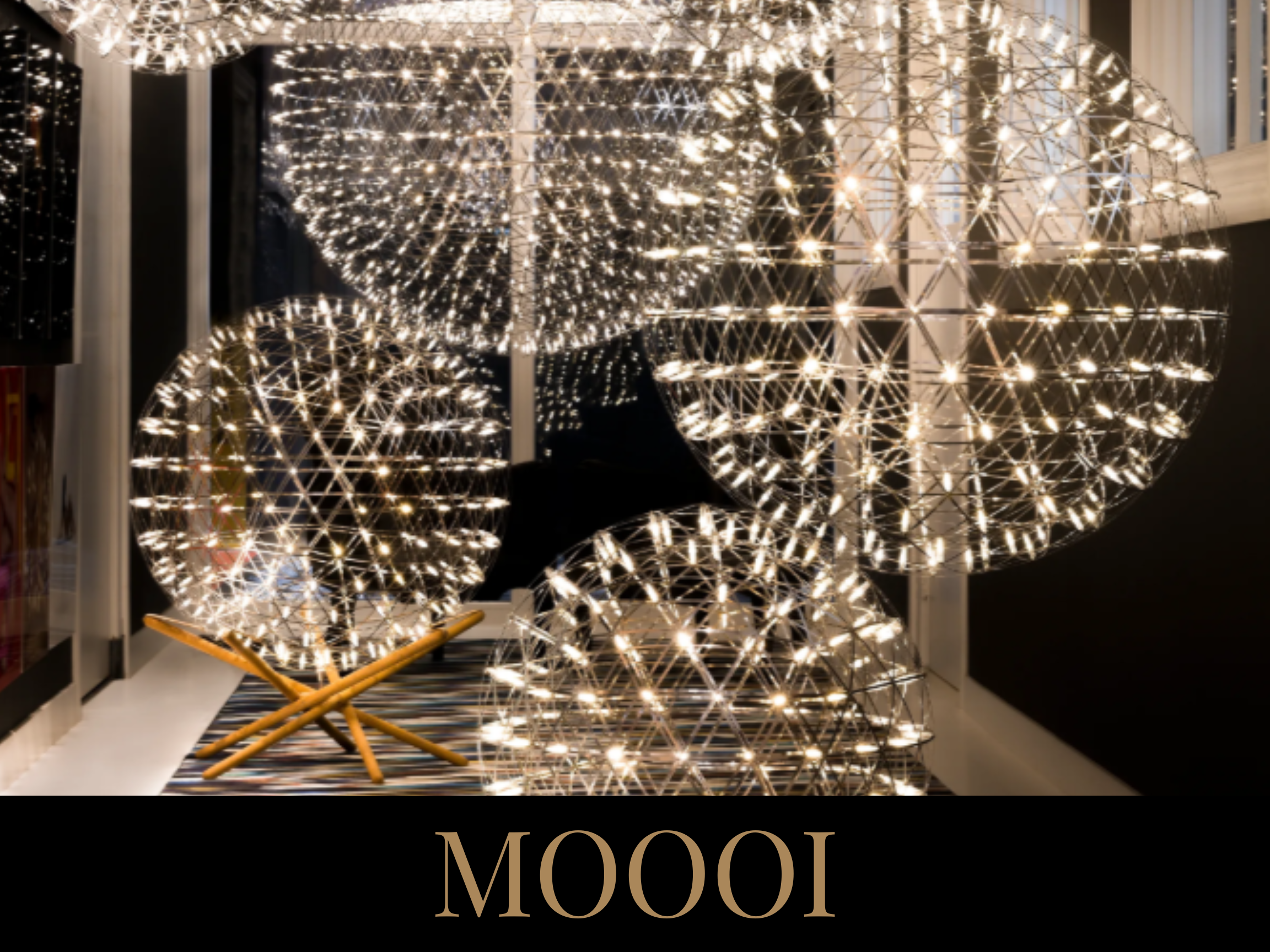 Decorative illuminated spherical ornaments resembling globes, displayed on a striped rug, with the word 'MOOI' at the bottom.
