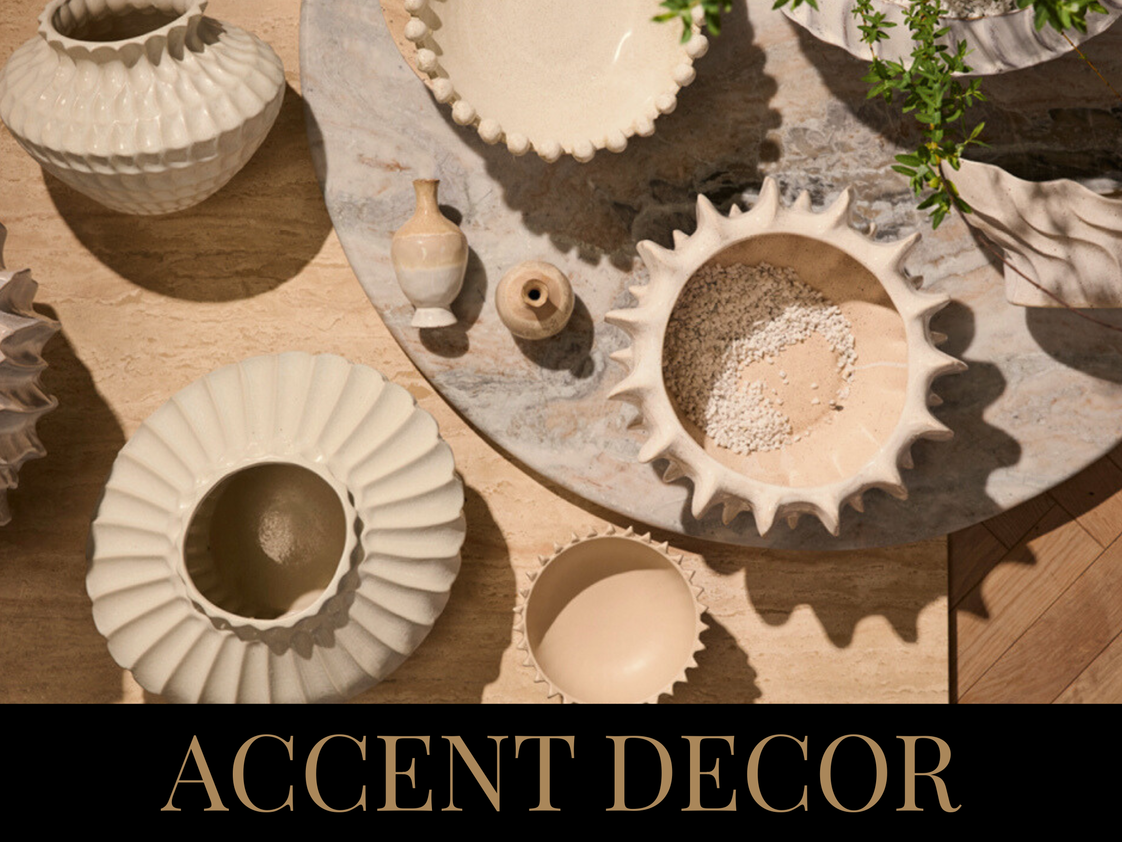 Various white ceramic and clay vases and bowls with textures and patterns, arranged on a marble and wooden surface, with greenery in the background.