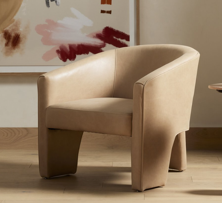 Beige upholstered armchair in a modern interior with abstract art on the wall.
