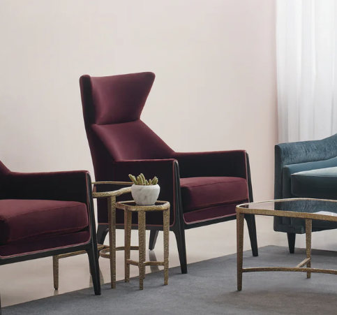 Living room with burgundy and blue armchairs, a small side table with a plant, and a glass-top coffee table.