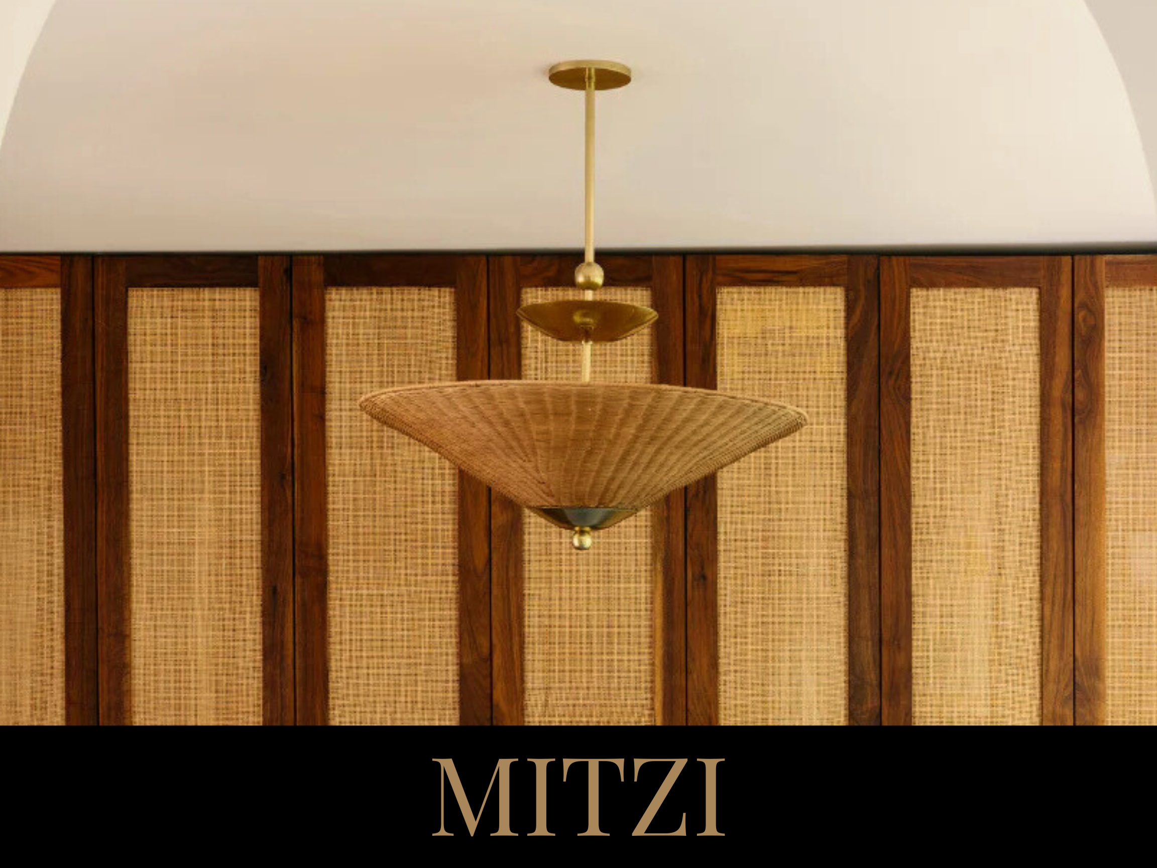 Close-up of a vintage pendant light fixture with a woven rattan shade hanging from a ceiling, against a wooden paneled wall with woven textured panels underneath, with the word "MITZI" written in large beige letters at the bottom.