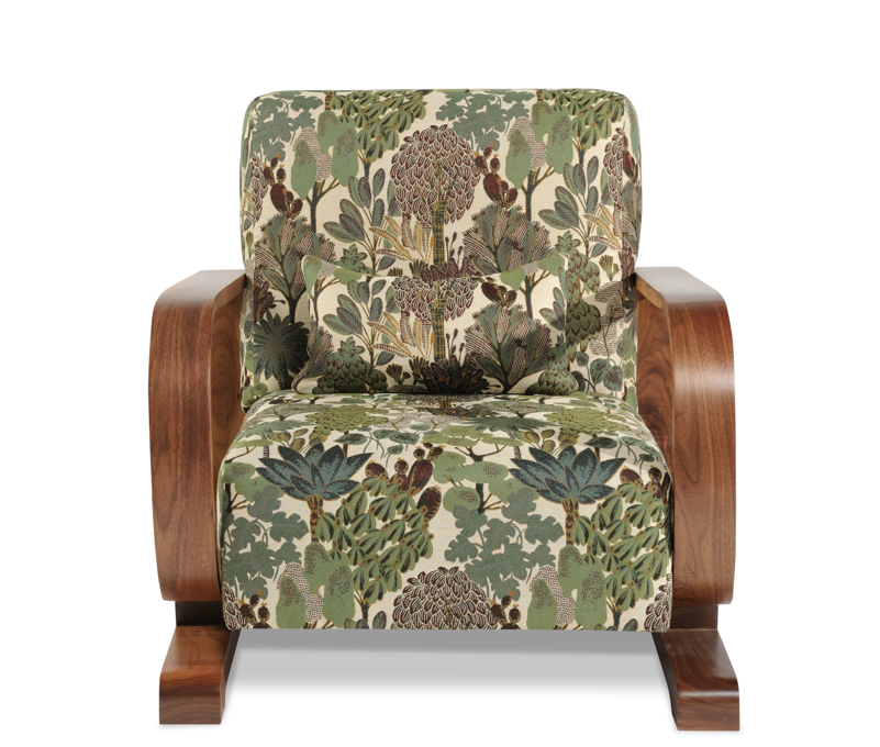 An armchair with a floral and leafy patterned fabric and wooden armrests.