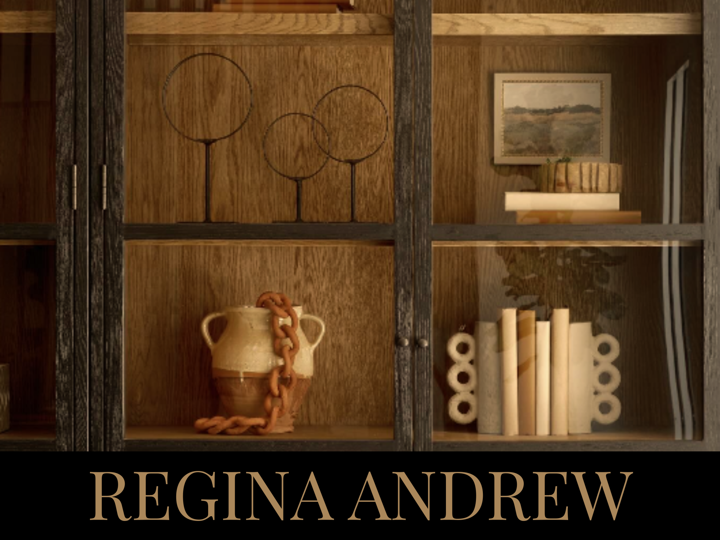 A wooden display cabinet with decorative items including a brown and beige ceramic vase with a large chain on it, a set of white and gold candles, a small framed landscape painting, and a potted plant inside.