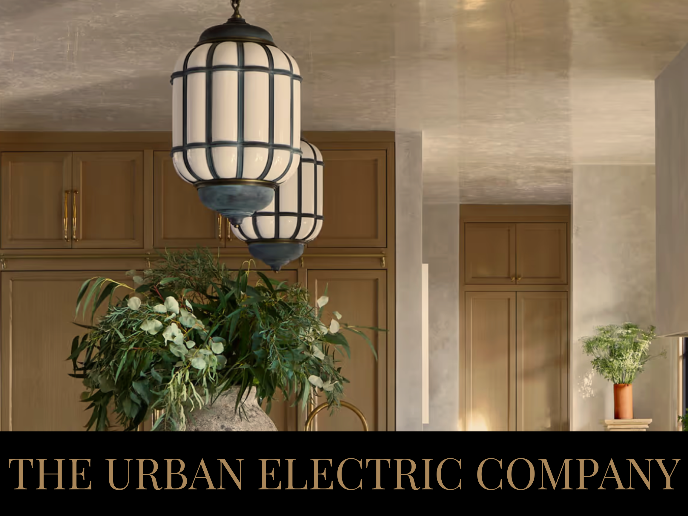 Interior of a modern kitchen with beige walls, wooden cabinets, pendant lights, and decorative plants.