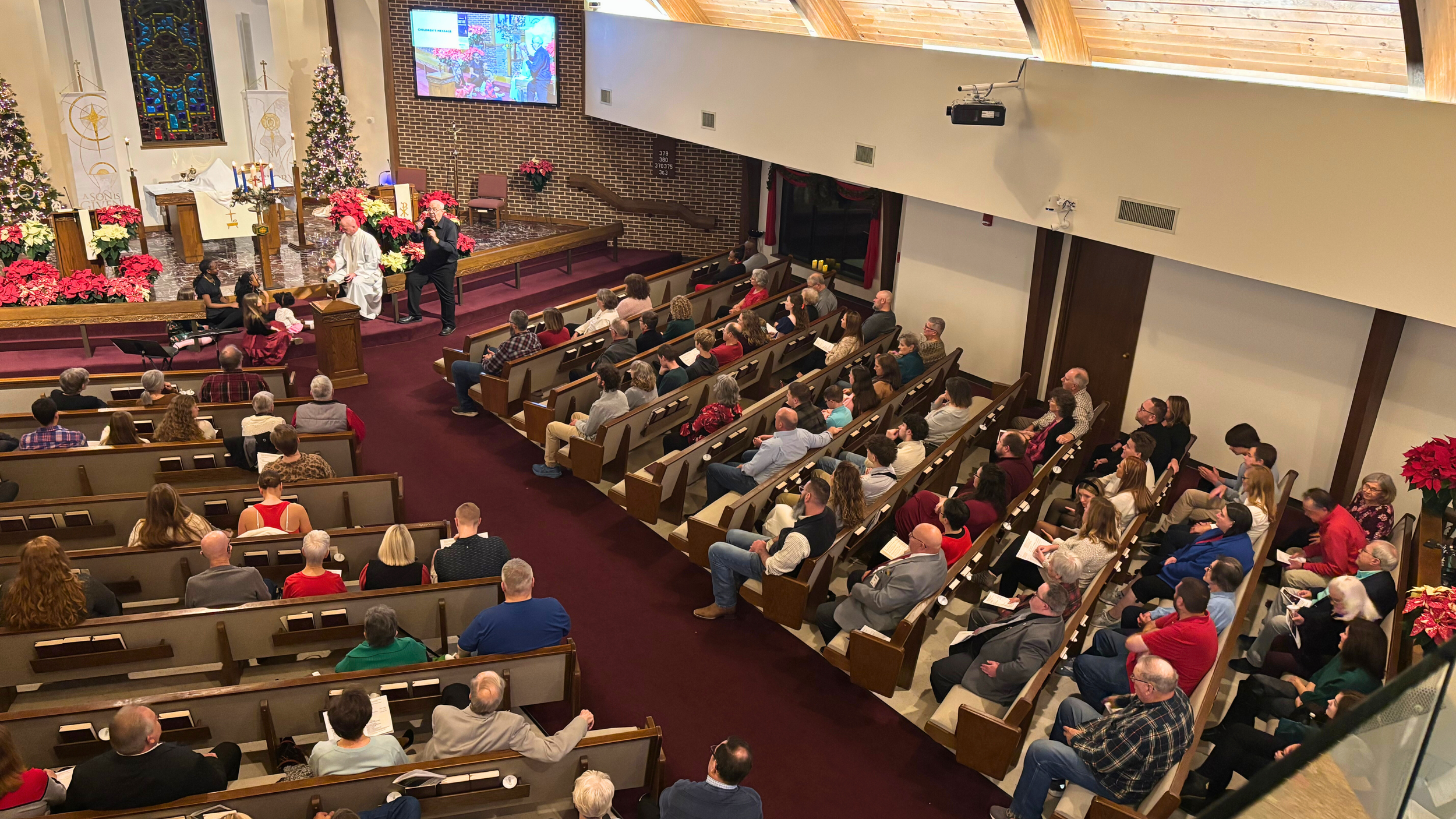 Overhead view of Redeemer Lutheran Church sanctuary during Christmas service, showing the congregation gathered for worship, festive decorations, and a celebration of Christ’s birth.