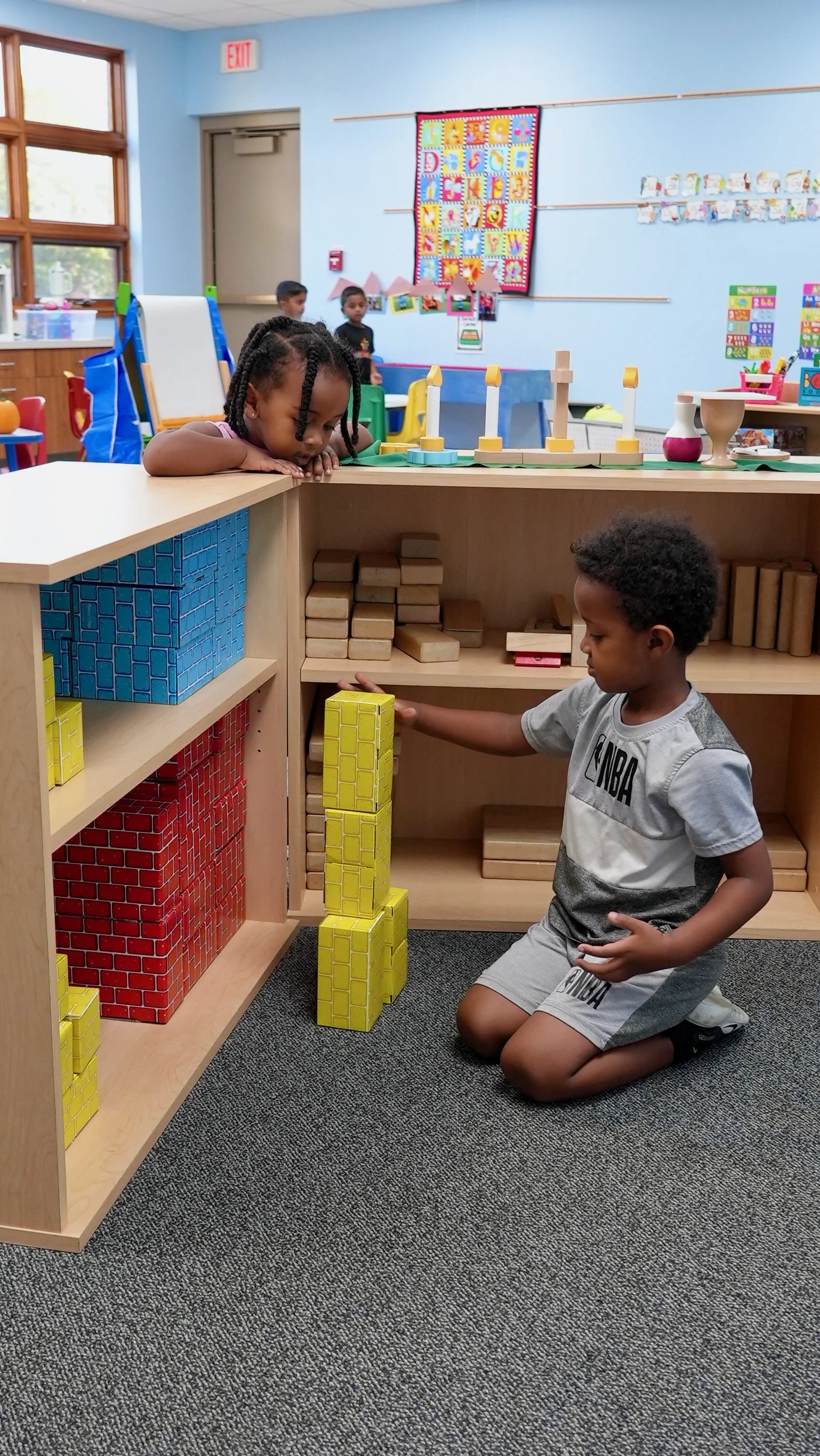 Students at Redeemer Lutheran Preschool playing with building blocks in a classroom filled with colorful educational decorations and child-friendly furniture, fostering learning and creativity in a faith-based environment.