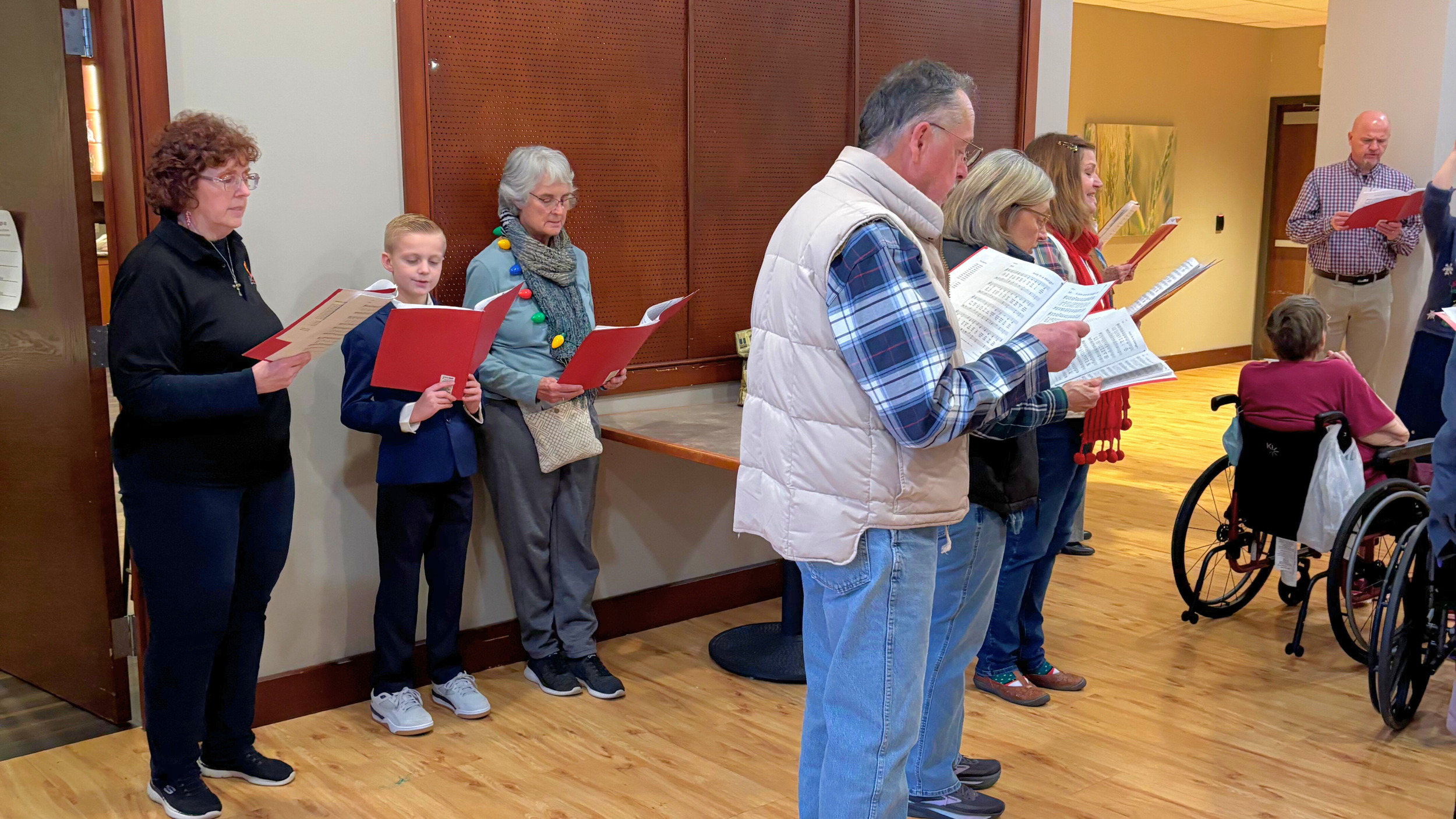 Church members from Redeemer Lutheran Church performing Christmas carols at a nursing home, engaging with seniors and sharing the spirit of the season.