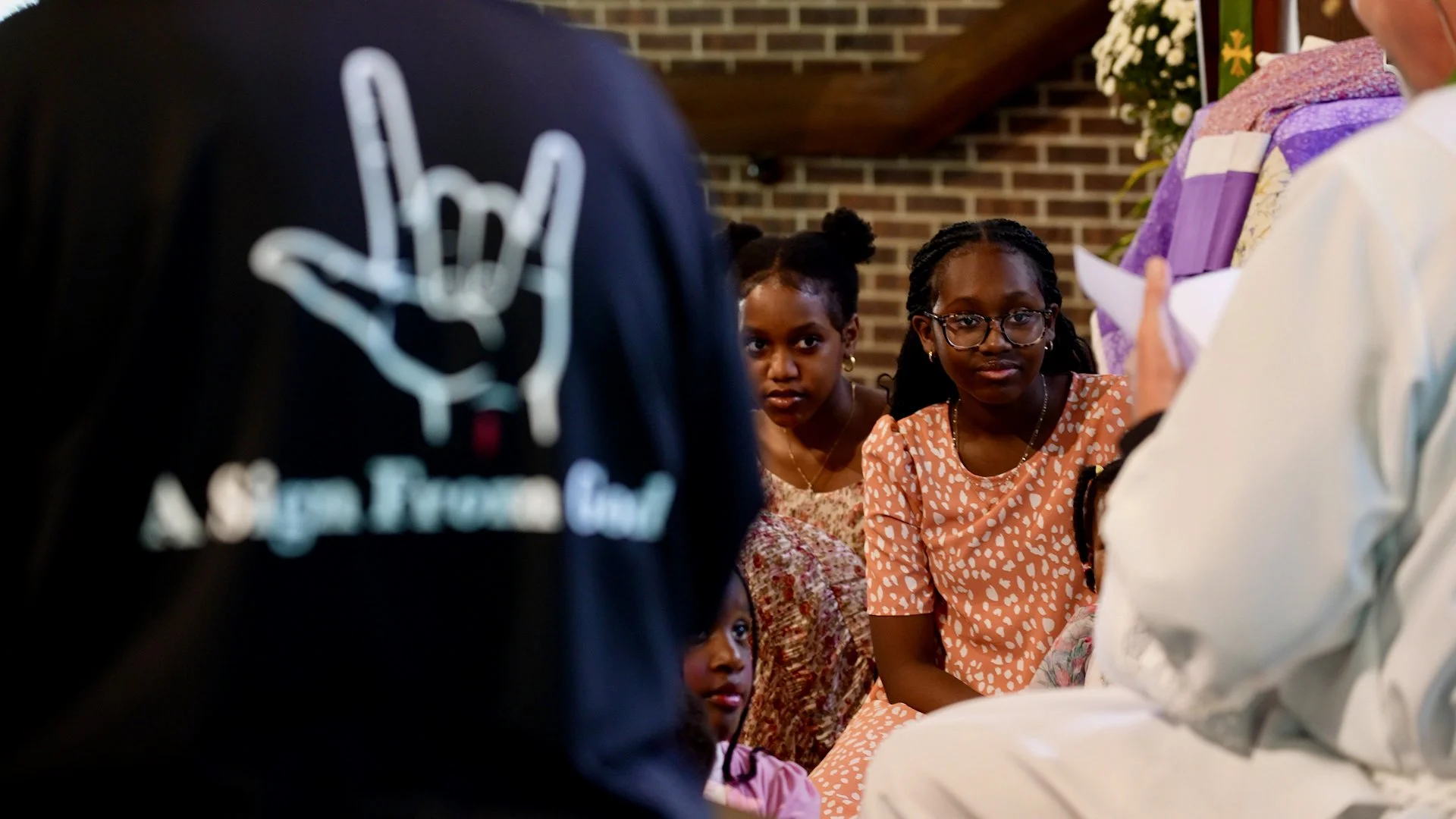 Children participating in the Deaf Ministry at Redeemer Lutheran Church, sitting attentively during a gathering while an adult leads the discussion.