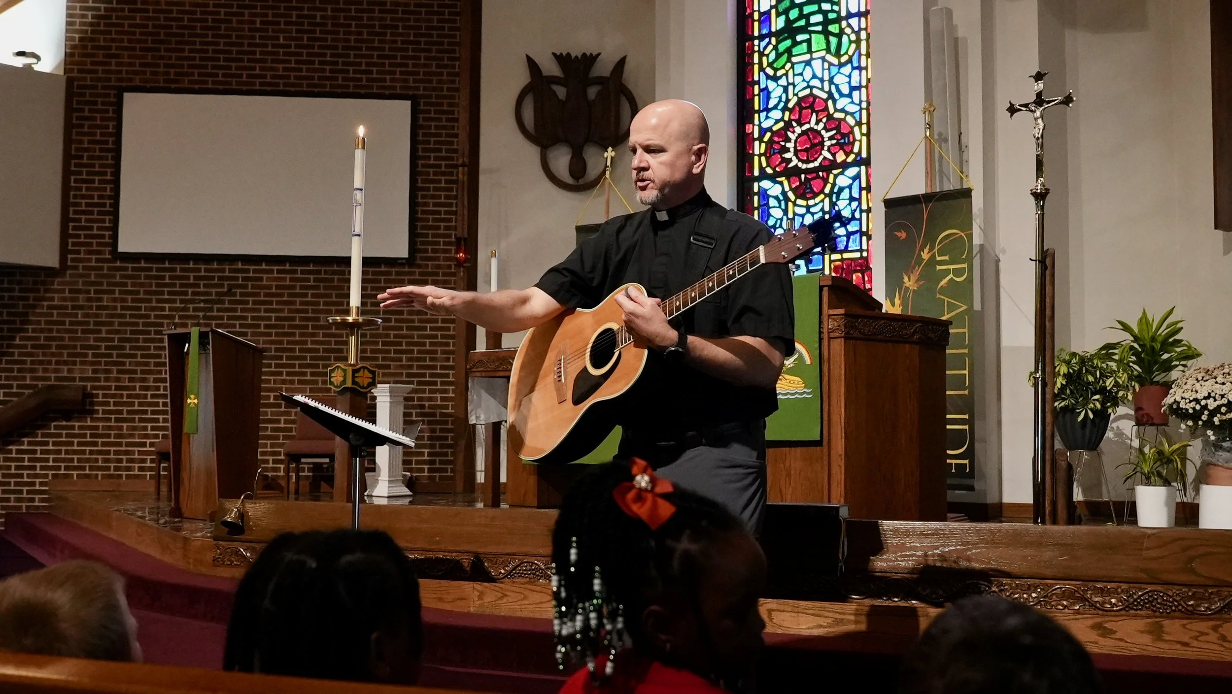 Redeemer Lutheran Church worship service: Pastor playing acoustic guitar on stage, leading the congregation in music and praise.