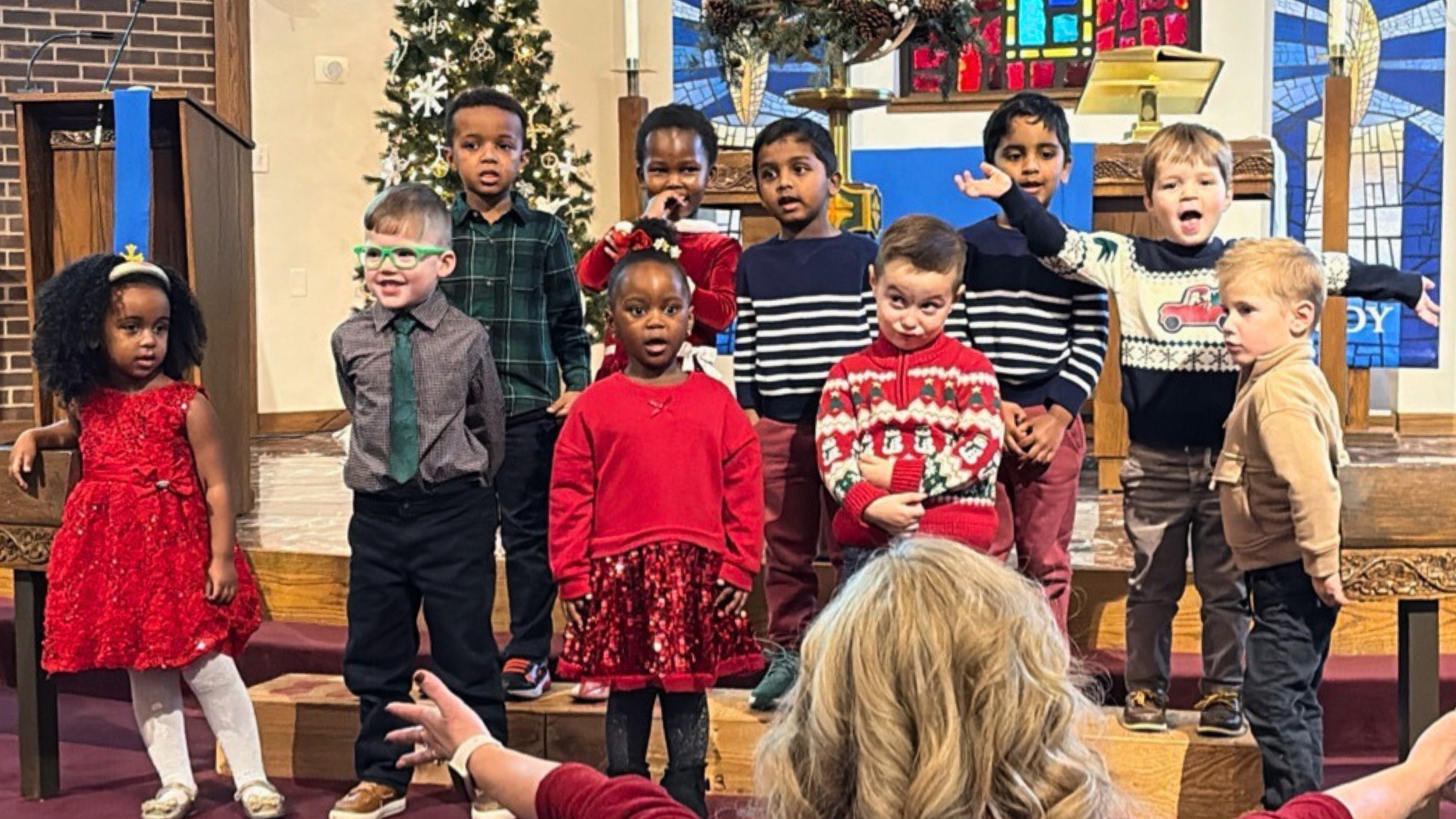 Preschoolers from Redeemer Lutheran Preschool singing at a Christmas service at Redeemer Lutheran Church in Kansas City, dressed in festive holiday attire.